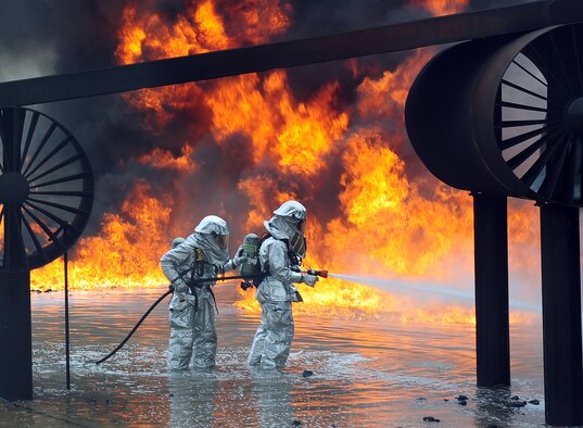 U.S. Air Force firefighters from the 7th Civil Engineer Squadron spray water onto a fire during a live fire training exercise April 2, 2014, at Dyess Air Force Base, Texas. In addition to wearing their fire proximity suits, firefighters must also wear self-contained breathing apparatus’ that provide a source of clean oxygen, enabling them to work in the presence of smoke or other super-heated gases.  (U.S. Air Force photo by Senior Airman Kia Atkins/Released)