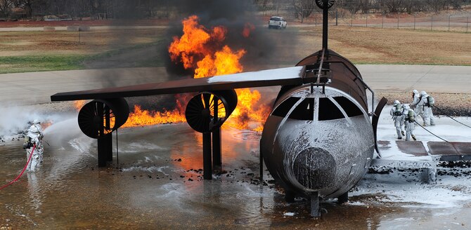 Firefighters from the 7th Civil Engineer Squadron and the Abilene Fire Department participate in live fire training exercise April 2, 2014, at Dyess Air Force Base, Texas. The firefighters also used foam to suppress the fire. Foam cools the fire and coats the fuel, preventing its contact with oxygen, resulting in suppression of the combustion. (U.S. Air Force photo by Senior Airman Kia Atkins/Released)