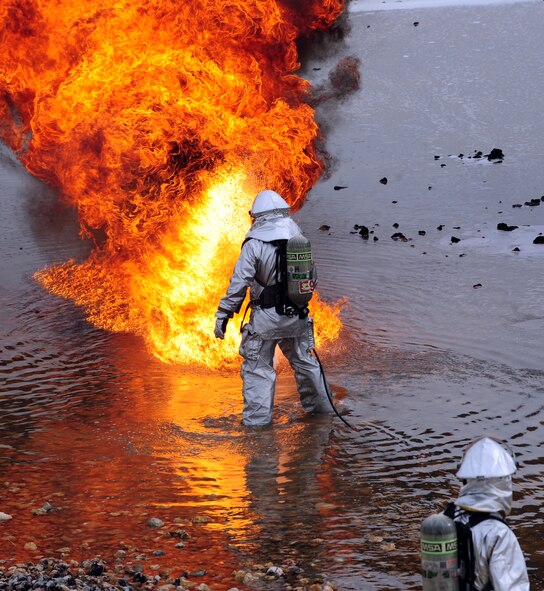 A U.S. Air Force firefighter from the 7th Civil Engineer Squadron ignites jet fuel during live fire training exercise April 2, 2014, at Dyess Air Force Base, Texas. The silver suits that firefighters wear are called fire proximity suits, which are designed to protect them from fire and extreme heat, like the heat encountered during aircraft fires. (U.S. Air Force photo by Senior Airman Kia Atkins/Released)