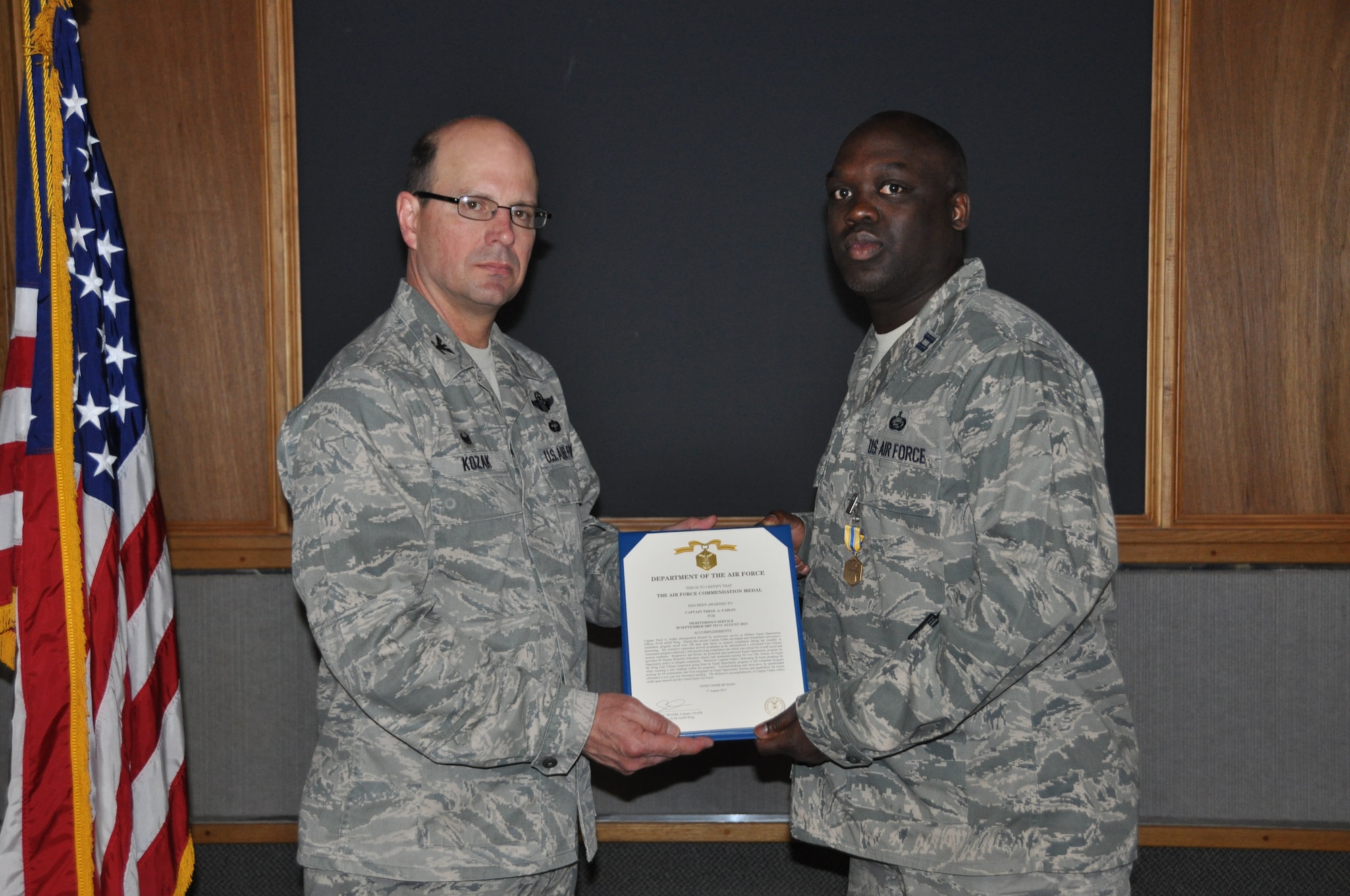 Col. Raymond A. Kozak, 512th Airlift Wing commander, presents a certificate for the Air Force Commendation Medal to Capt. Theol Fadlin, 512th AW Equal Opportunity director, April 5, 2014, at Dover Air Force Base, Del. The award was in recognition of his meritorious service as a military equal opportunity officer during the period of September 2007 to August 2013. (Air Force photo by Senior Airman Joe Yanik)