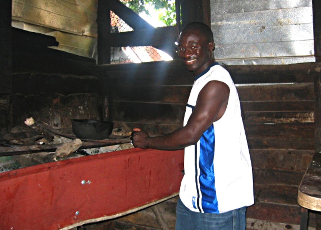 U.S. Air Force Master Sgt. Kenry Peart, 633rd Communications Squadron knowledge operations section chief, cooks on the wood-burning stove in the Parish of Manchester, Jamaica in this undated photo. Growing up, Peart worked with his family cooking meals, farming the fields and raising livestock. (Courtesy photo)