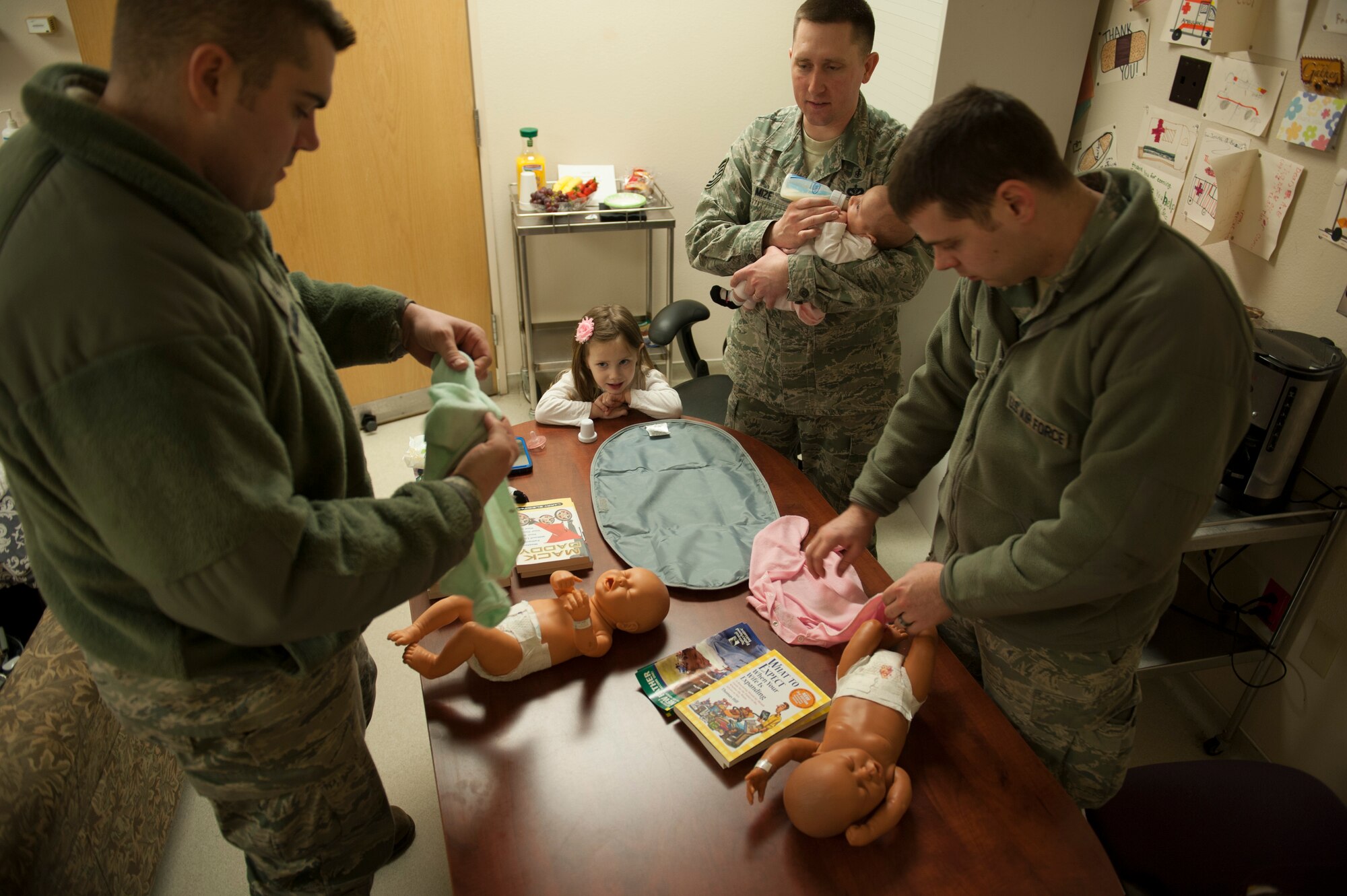 U.S. Air Force Tech. Sgt. Dustin Mize, NCO in charge of ambulance services from the 5th Medical Group, watches over soon-to-be fathers on Minot Air Force Base, N.D., April 1, 2014. The fathers practiced clothing, swaddling and changing diapers on dolls in preparation for their newborns. (U.S. Air Force photo/ Airman 1st Class Sahara L. Fales)