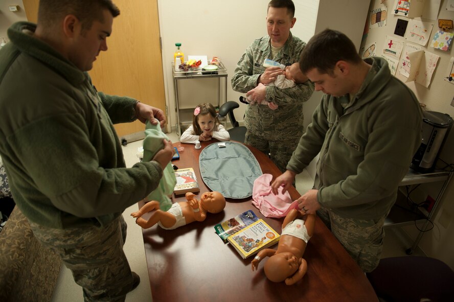 U.S. Air Force Tech. Sgt. Dustin Mize, NCO in charge of ambulance services from the 5th Medical Group, watches over soon-to-be fathers on Minot Air Force Base, N.D., April 1, 2014. The fathers practiced clothing, swaddling and changing diapers on dolls in preparation for their newborns. (U.S. Air Force photo/ Airman 1st Class Sahara L. Fales)