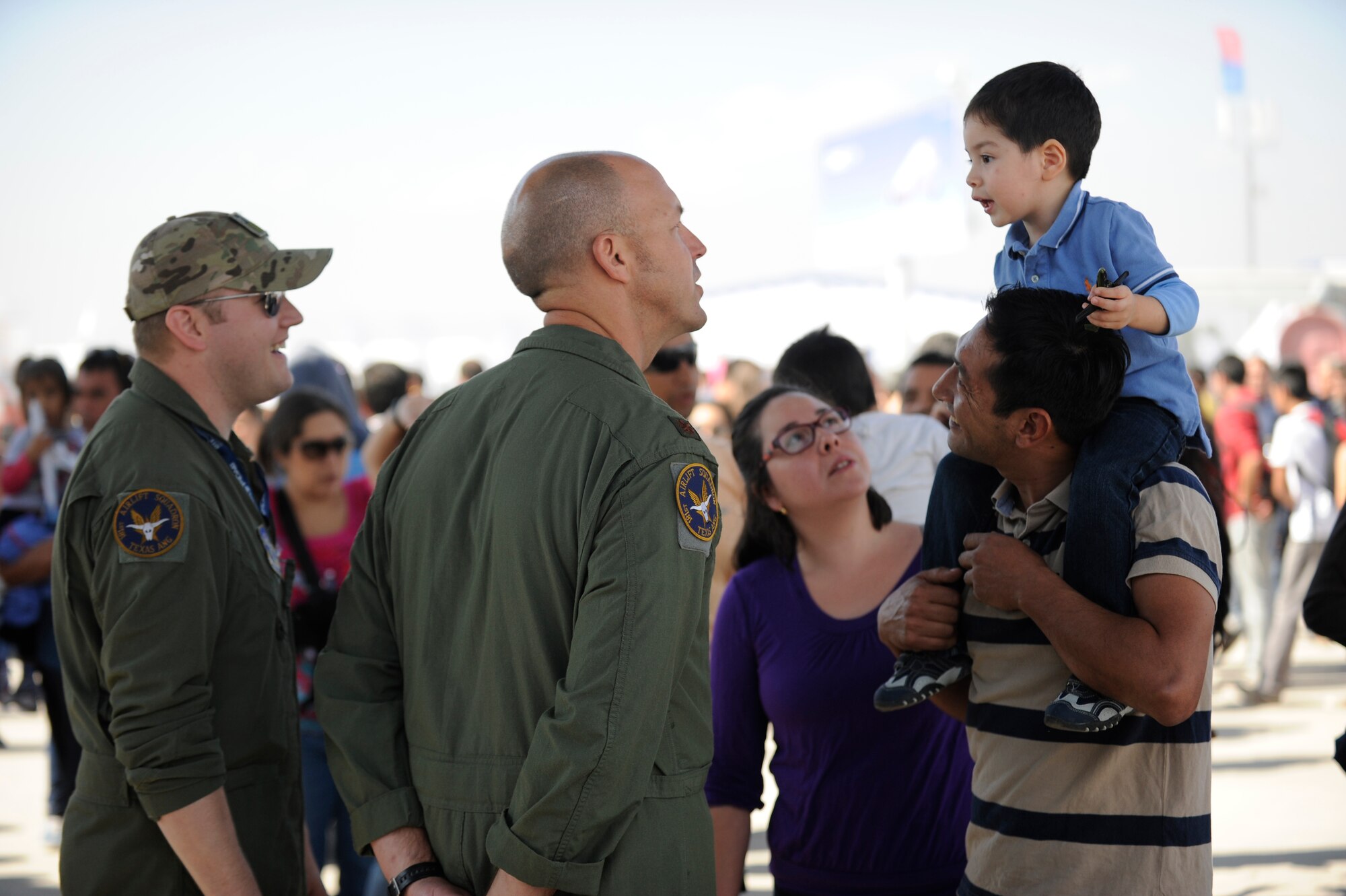 Tech. Sgt. Brian Krause and Maj Josh Ritzmann, members of the 136th Airlift Wing, attempt to communicate with a young local visitor enjoying FIDAE (Feria Internacional del Aire y del Espacio), an international trade exhibition air and space show, in Santiago, Chile, March 29, 2014. Krause and Ritzmann were in Chile with other members of the Texas Air National Guard for a subject matter expert exchange through the National Guard Bureau's State Partnership Program. (U.S. Air National Guard photo by Senior Master Sgt. Miguel Arellano / Released)