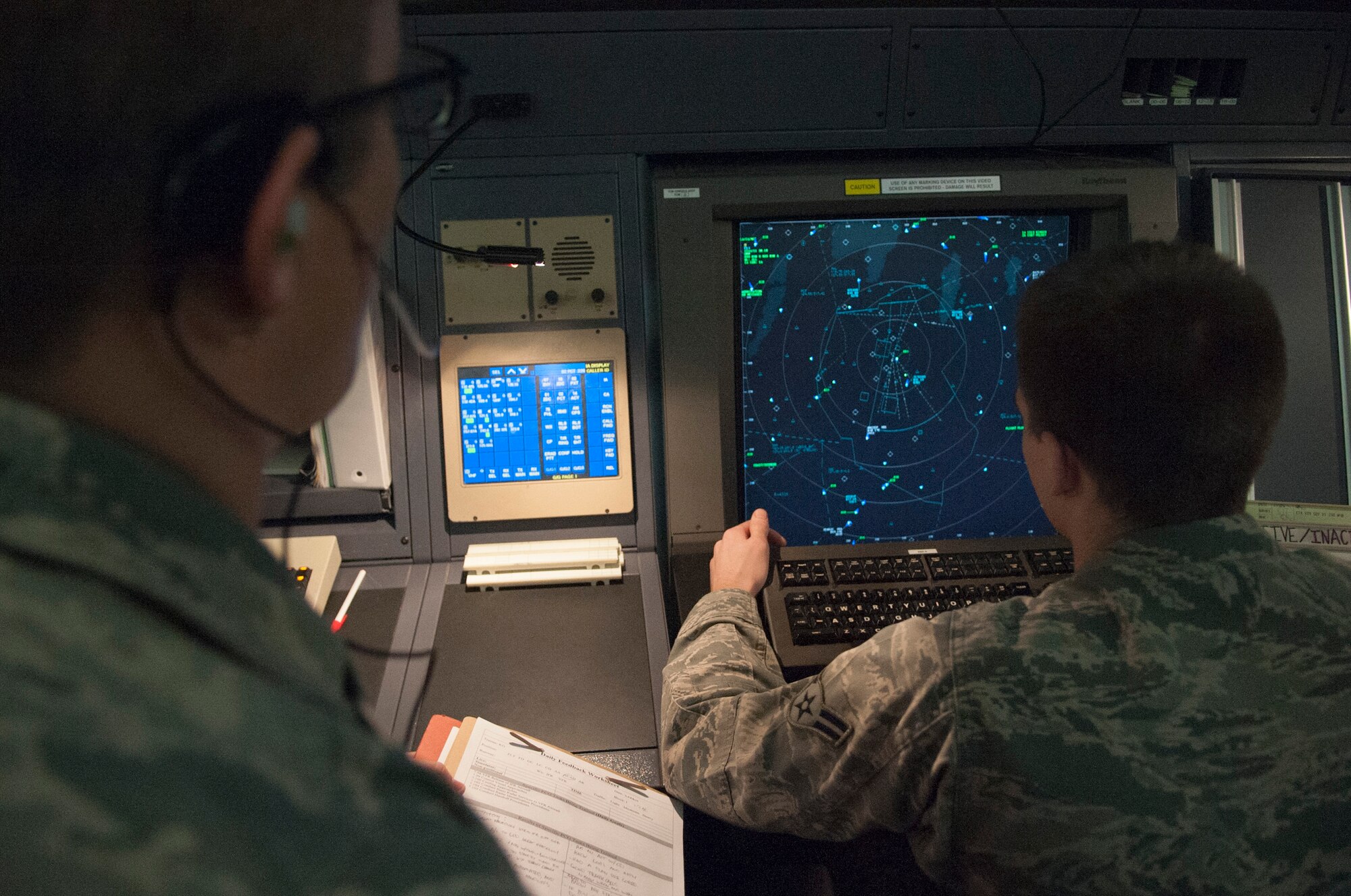 A radar approach controller monitors a trainee while he attempts to control air traffic April 2, 2014, at Dover Air Force Base, Del. A RAPCON controller must be confident, knowledgeable and signed off on all training requirements before they are allowed to work without a trainer. (U.S. Air Force photo/Senior Airman Jared Duhon)