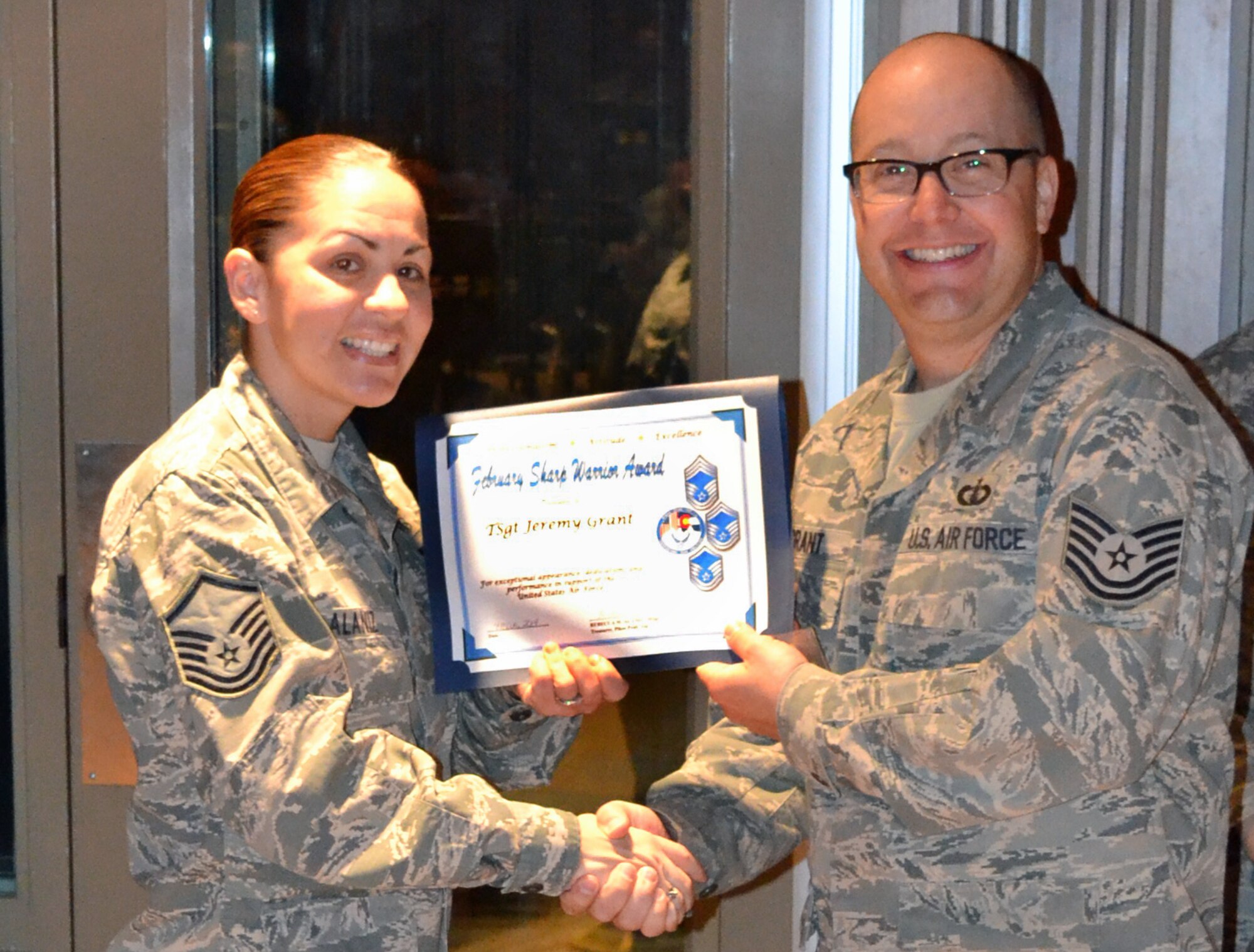 PETERSON AIR FORCE BASE, Colo. – Master Sgt. Rebecca Alaniz, on behalf of the Pikes Peak Top 3, presents the February 2014 Sharp Warrior Award to Tech. Sgt. Jeremy Grant, U.S. Air Force Academy Band. Grant performed flawlessly as a soloist with the 49-member concert band at Festival of Winds which reached 500 potential USAFA and Air Force recruits. He also led a six-member administration section during an unprecedented personnel turnover. Additionally, Grant aided nine members in reviewing and updating their personnel records for the Enlisted Retention Boards, which resulted in his selection as February’s Sharp Warrior. (U.S. Air Force photo)