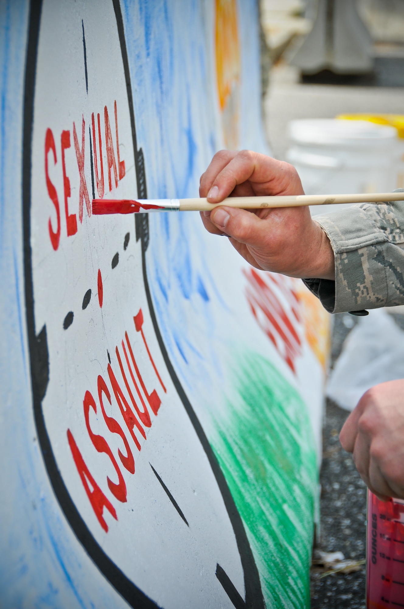 A picture of U.S. Air Force Staff Sgt. Anthony Foster from the 177th Fighter Wing paints the words "sexual assault" inside of a painting of a cross hair.