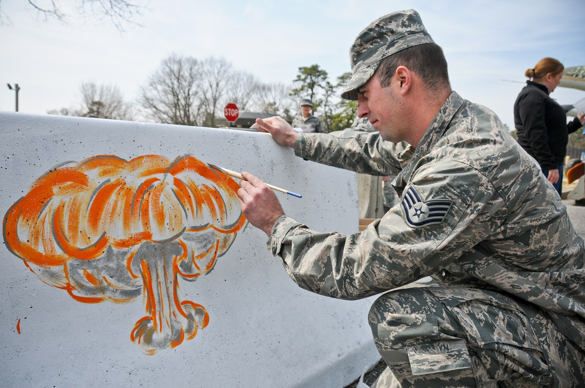A picture of U.S. Air Force Staff Sgt. Anthony Foster from the 177th Fighter Wing painting a mushroom cloud onto a barrier.