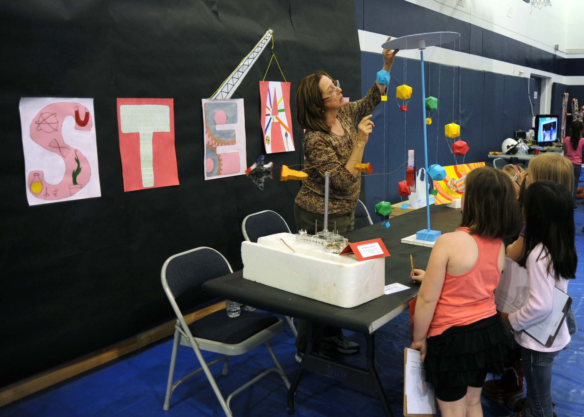 INCIRLIK AIR BASE, Turkey--Roberta Evans, Incirlik Unit School art teacher, shows students examples of how art is used to collaborate with scientists, mathematicians and engineers at the Science, Technology, Engineering, and Math fair held April 4, 2014, Incirlik Air Base, Turkey. More than 30 volunteers from various units assisted with set-up, logistical support, and presentations for the event. (U.S. Air Force photo by Staff Sgt. Veronica Pierce)