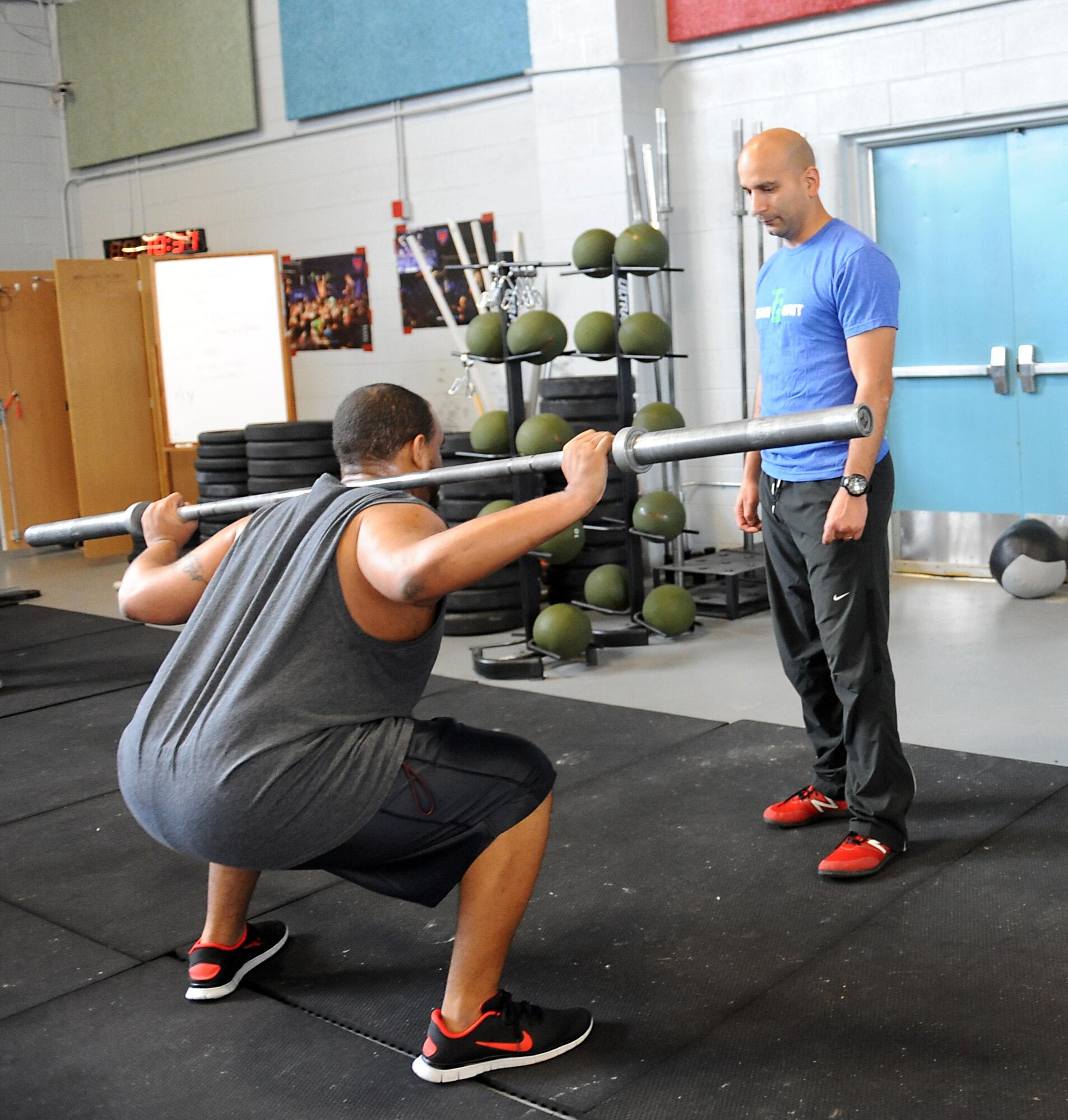 U.S. Marine Corps Gunnery Sgt. Juan Ospina, Joint Task Force Civil Support operations noncommissioned officer in charge, ensures a participant's proper physical technique while performing a squat exercise during a CrossFit session held at the Anderson Field House at Fort Eustis, Va., March 19, 2014. Ospina is the JTF-CS physical training promotion coordinator and the lead Fort Eustis CrossFit instructor. He believes physical fitness enhances unit readiness by promoting team cohesion and mental alertness. (Department of Defense photo by U.S. Air Force Tech. Sgt. Gwendolyn Blakley/Released)
