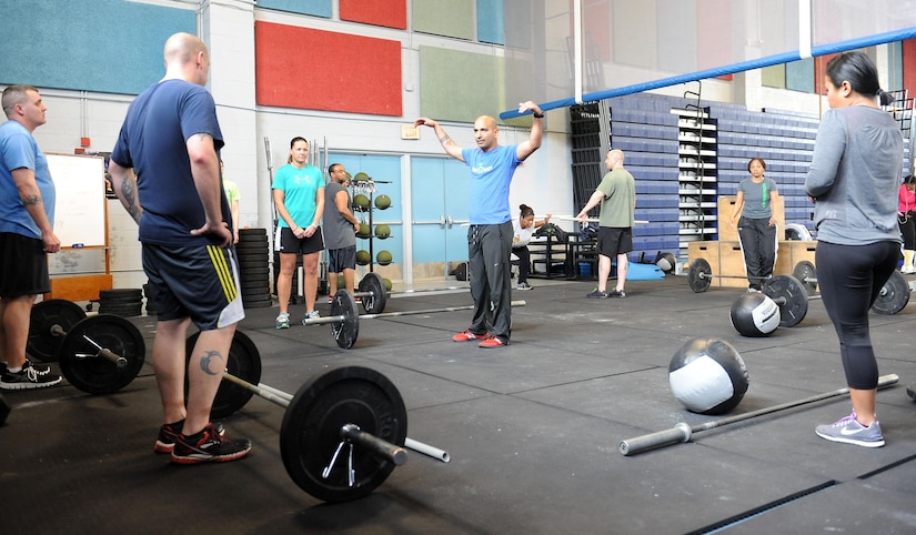 U.S. Marine Corps Gunnery Sgt. Juan Ospina, Joint Task Force Civil Support operations noncommissioned officer in charge, provides instructions on correct hand placement to perform overhead squats during a CrossFit session at the Anderson Field House at Fort Eustis, Va., March 19, 2014. Ospina is the JTF-CS physical training promotion coordinator and the lead Fort Eustis CrossFit instructor. He believes physical fitness enhances unit readiness by promoting team cohesion and mental alertness. (Department of Defense photo by U.S. Air Force Tech. Sgt. Gwendolyn Blakley/Released)