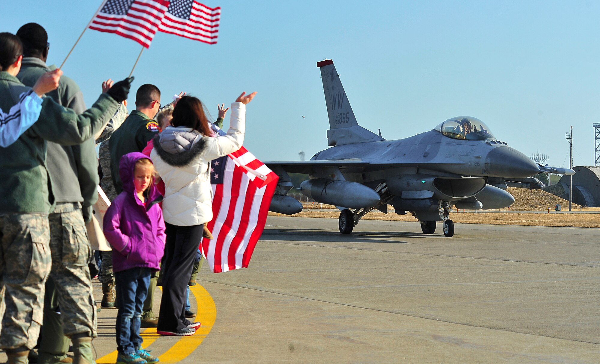 Family and friends of F-16 Fighting Falcons pilots assigned to the 13th Fighter Squadron wave goodbye to a pilot at Misawa Air Base, Japan, April 8, 2014. More than 70 met at the base flightline to bid farewell to the team of Wild Weasels heading for deployment. (U.S. Air Force photo/Senior Airman Jose L. Hernandez-Domitilo)