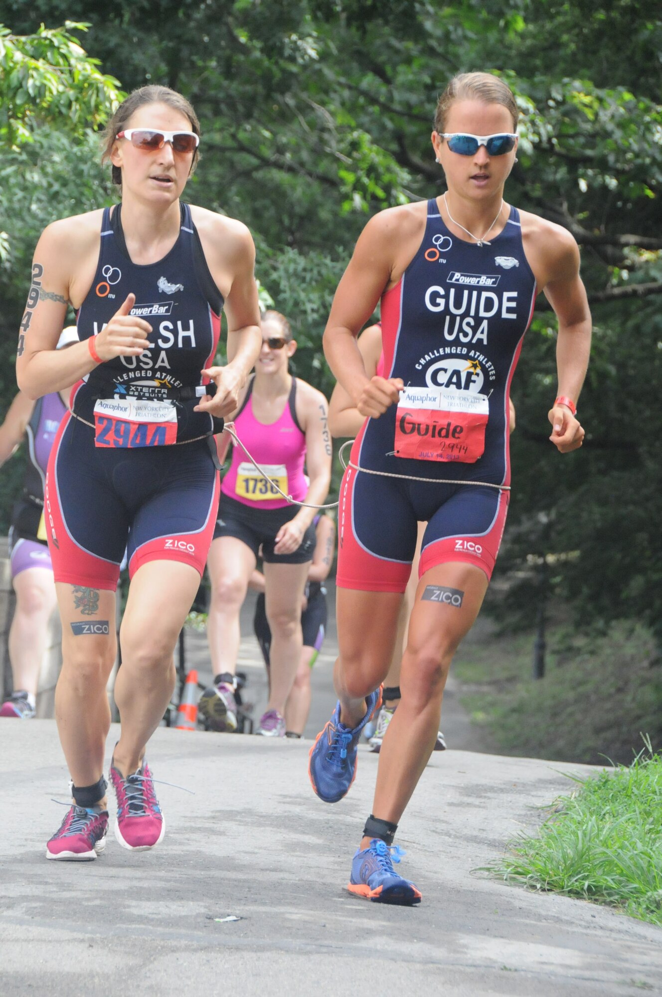 Tethered at the waist, 2nd Lt. Samantha Morrison (right) guides Patricia Walsh, a blind paratriathlete, through the 6.2 mile run of the New York City Triathlon July 14, 2013, in New York City, N.Y.  To prevent Walsh from going off course, Morrison would use the rope and her voice to guide Walsh through the entire race. 