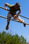 A Marine attending 2nd Marine Logistics Group’s Corporal’s Course climbs over a bar while completing an obstacle course challenge at Camp Lejeune, N.C., March 20, 2014. Instructors at the course paired hands-on physical training with daily classroom instruction to challenge their students throughout the course.