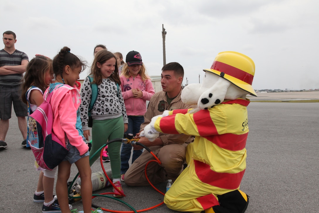 Lance Cpl. Braxtyn F. Sinclair and Sparky the Fire Safety Dog demonstrate how to use the controls for a lifting air bag April 7 at the fire station on Marine Corps Air Station Futenma during a visit from Girl Scouts. The large air bags are used when a car, or similarly heavy item, needs to be lifted off the ground. The Marines showed visiting Girl Scouts the equipment they use when responding to an emergency, such as the P-19A fire truck, proximity rescue suits they wear, and hydraulic tools that cut metal to assist in rescues. Sinclair is an aircraft rescue and firefighting specialist ARFF, Headquarters and Headquarters Squadron, MCAS Futenma, Marine Corps Installations Pacific, and Sparky is the mascot for the National Fire Protection Association.