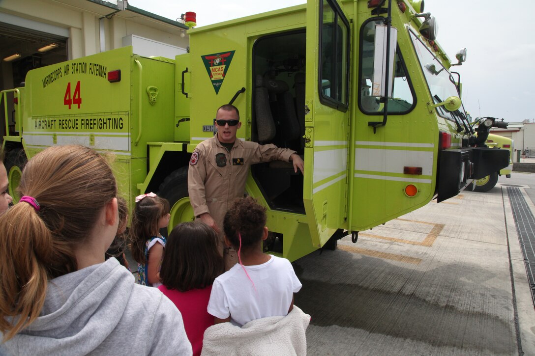 Lance Cpl. Jacob P. Sicard discusses the capabilities of a P-19A fire engine at the fire station on Marine Corps Air Station Futenma April 7 during a visit from Girl Scouts. The mission of Girl Scouts of America is to build the courage, confidence and character of girls, who can then make the world a better place, according to their website. Sicard is an aircraft rescue and firefighting specialist with ARFF, Headquarters and Headquarters Squadron, MCAS Futenma, Marine Corps Installations Pacific.