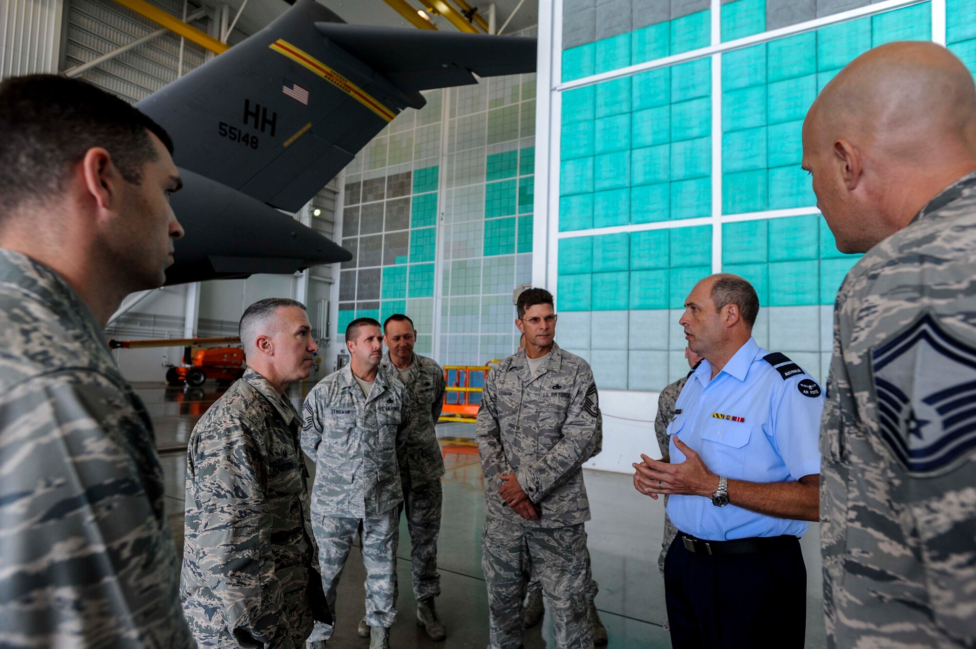 Commodore Peter Yates, Royal Australian Air Force general logistics director, asks questions about corrosion control and maintenance procedures during a briefing with 15th Maintenance Group leadership in Hangar 21 on Joint Base Pearl Harbor-Hickam, Hawaii, April 7, 2014. Yates is visiting JBPHH to conduct tactical-level discussions on how the RAAF and USAF can expand their interoperability in order to deliver seamless integration of forces.  (U.S. Air Force photo/Tech. Sgt. Terri Paden)