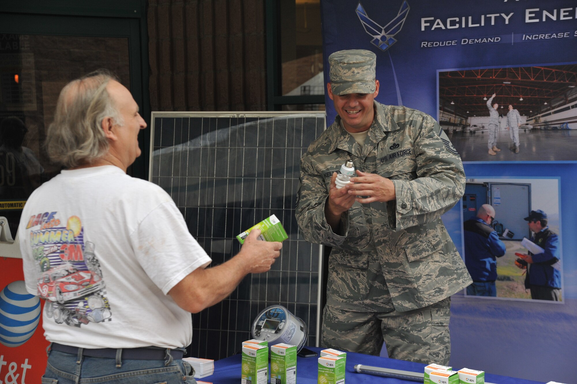 Master Sgt. Adam Kelley, 56th Civil Engineer Squadron base energy manager, explains the value of low wattage light bulbs to Robert Wimp at the energy conservation month booth at Luke Air Force Base, Ariz., April 9, 2014. (U.S. Air Force photo by Senior Airman Jason Colbert)