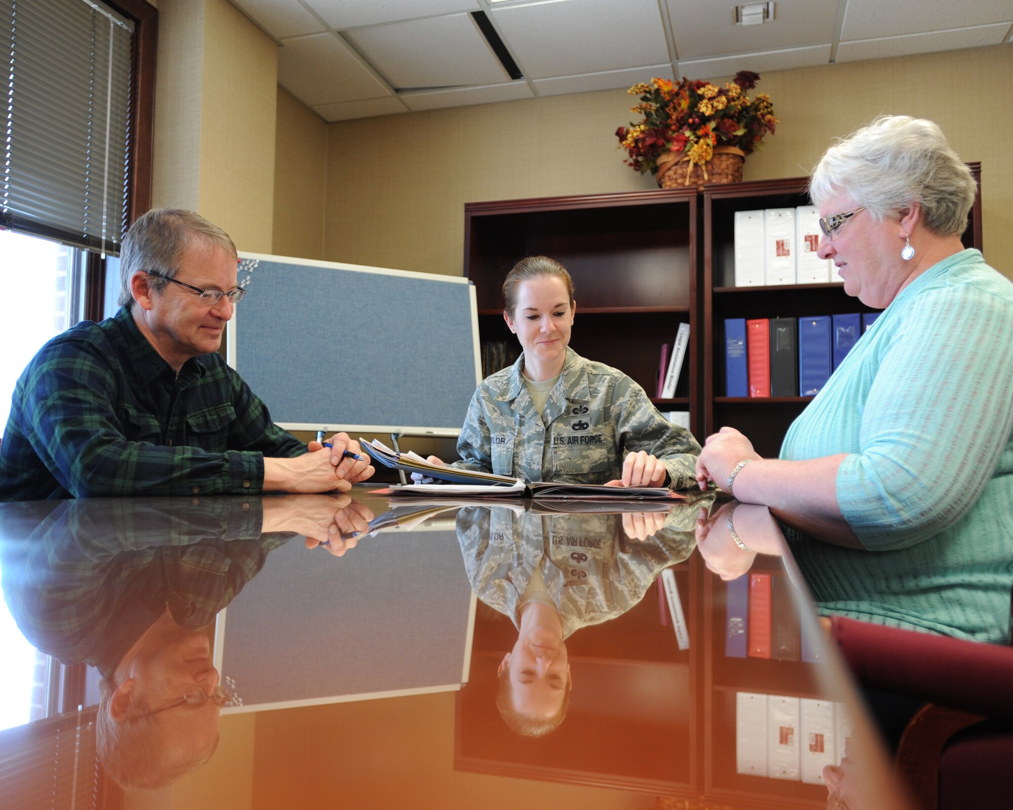 Mark Hanson, chief of general law at Grand Forks Air Force Base, N.D. (left), Master Sgt. Jessica Taylor, law office superintendant, and Marie Aubrey, legal assistant, discuss a case file April 8, 2014, at the base legal office. Hanson, Taylor and Aubrey were all selected to receive an Expeditionary Command level award for 2013. (U.S. Air Force photo/Senior Airman Zachiah Roberson)