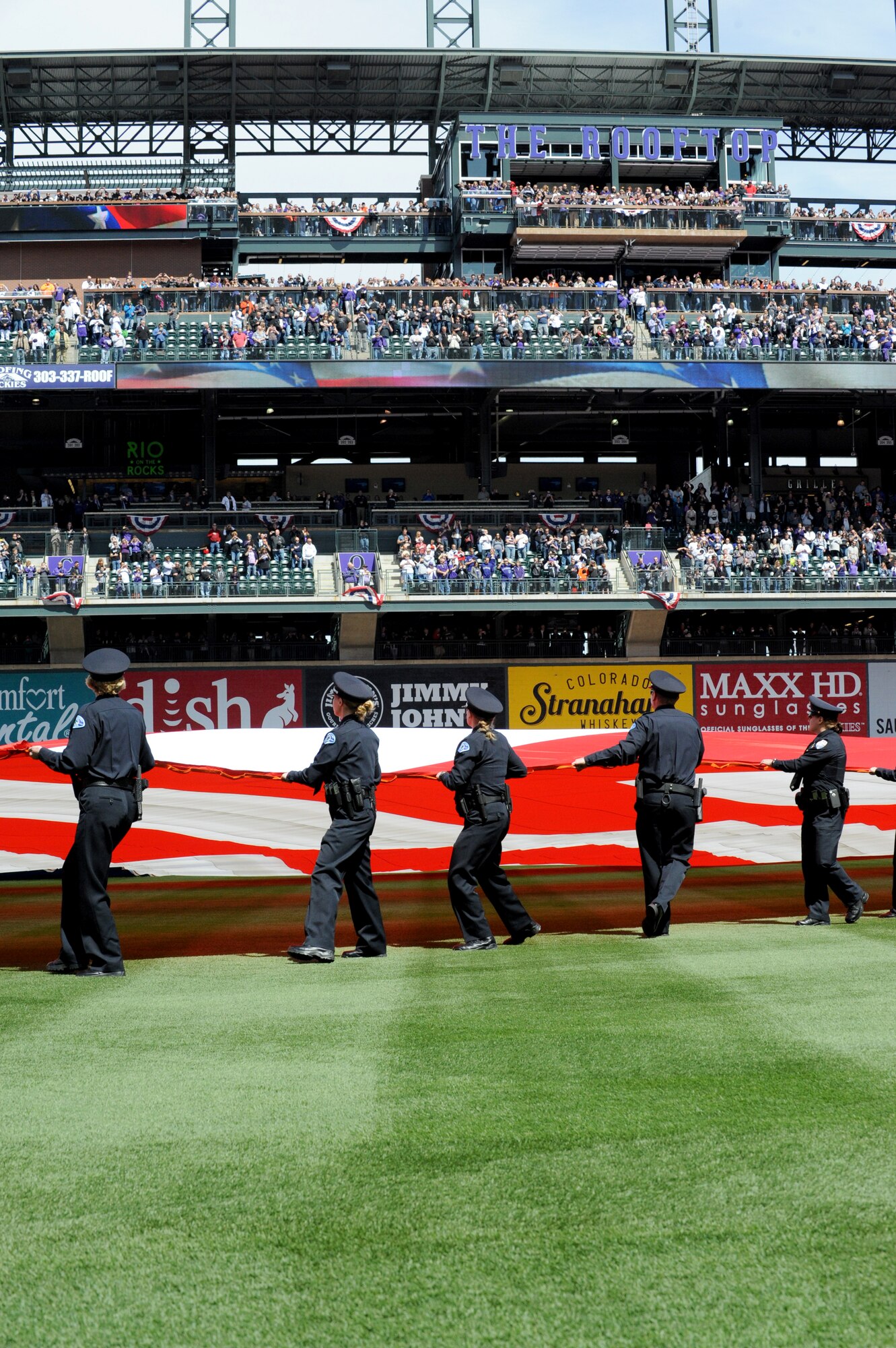 The American Flag is unfurled during the Colorado Rockies Opening Day ceremony April 4, 2014, at Coors Field, Denver. Service members from all U.S. military branches stood in formations as local law enforcement  and service members unfurled the American flag during the opening day ceremonies. (U.S. Air Force photo by Airman Emily E. Amyotte/Released)