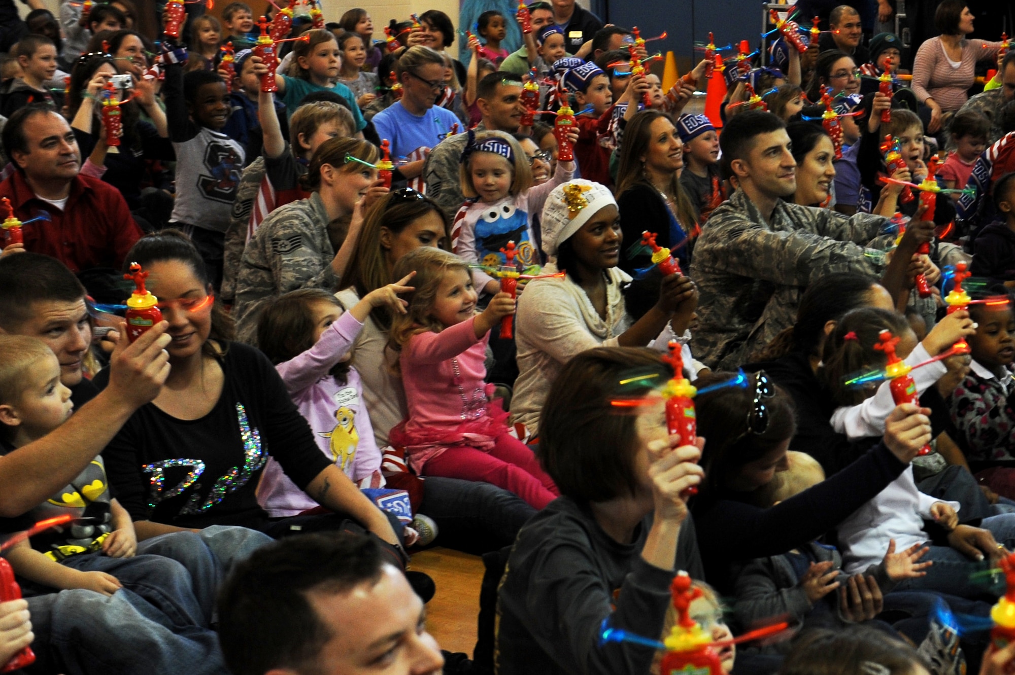 Families hold up their twirlers for a group photo. The interactive event featured dancing and singing with Sesame Street characters. (U.S. Air Force photo/ Airman 1st Class Megan Friedl)