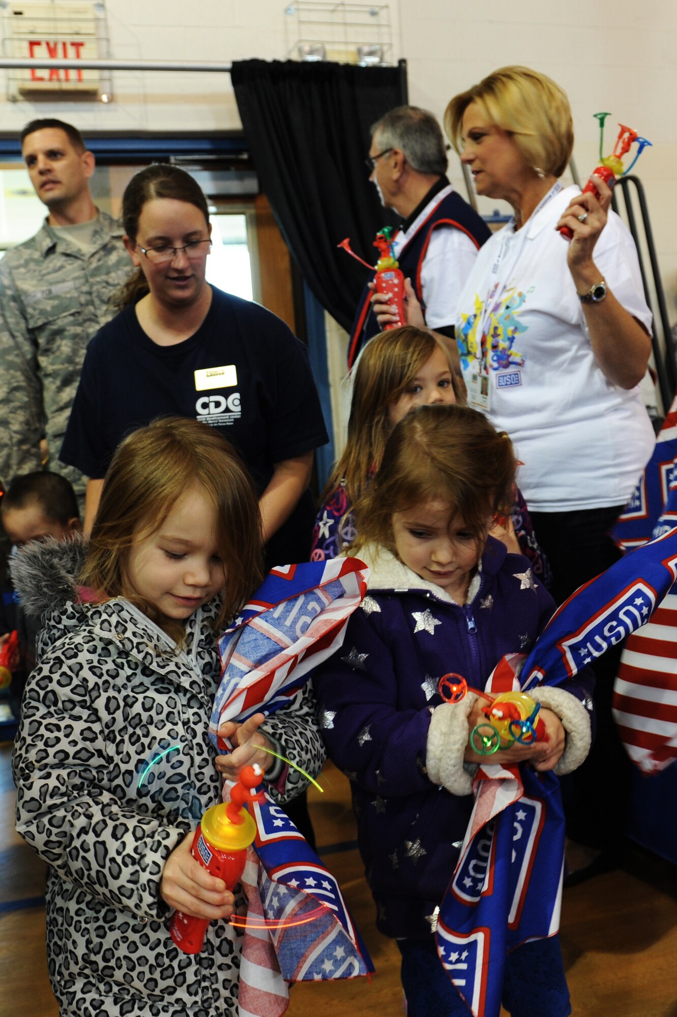 Children and their families receive gifts while walking into the Youth Center gym. All of the children received free bandannas, twirlers and resources to help with moving. (U.S. Air Force photo/ Airman 1st Class Megan Friedl)