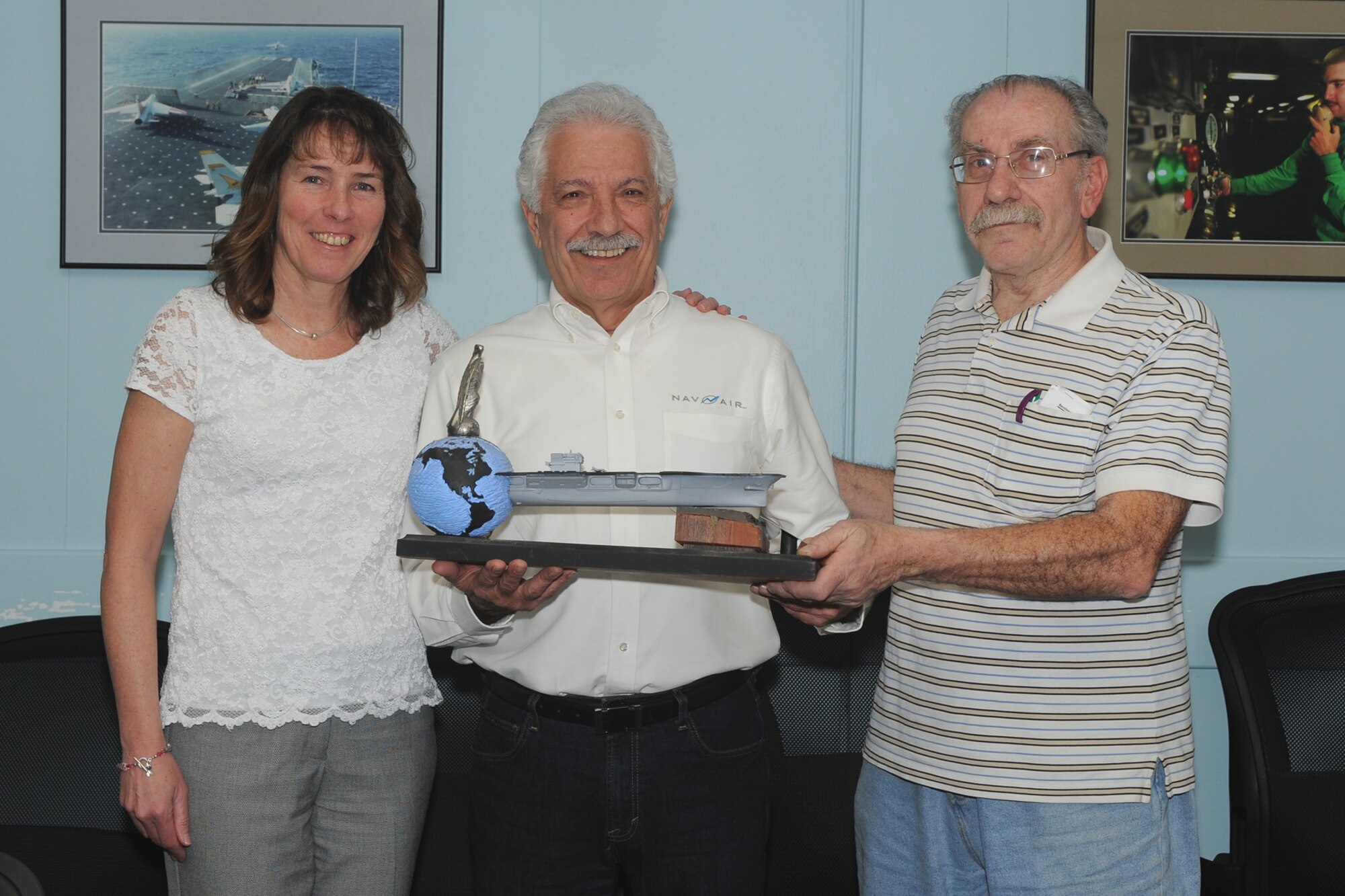 The Naval Air Warfare Center Aircraft Division at Joint Base McGuire-Dix-Lakehurst, N.J., hosted a ceremony on April 2,  to pass the Naval Air Engineering Center (NAEC) Honorary Plank from now retired Carmen Bentivegna (right) to Vince Strollo (center). The plank is presented to the NAVAIR Lakehurst Support Equipment and Aircraft Launch and Recovery Equipment Department (AIR 4.8) employee with the longest length of service. Kathy Donnelly, AIR 4.8 Director (left) led the ceremony.