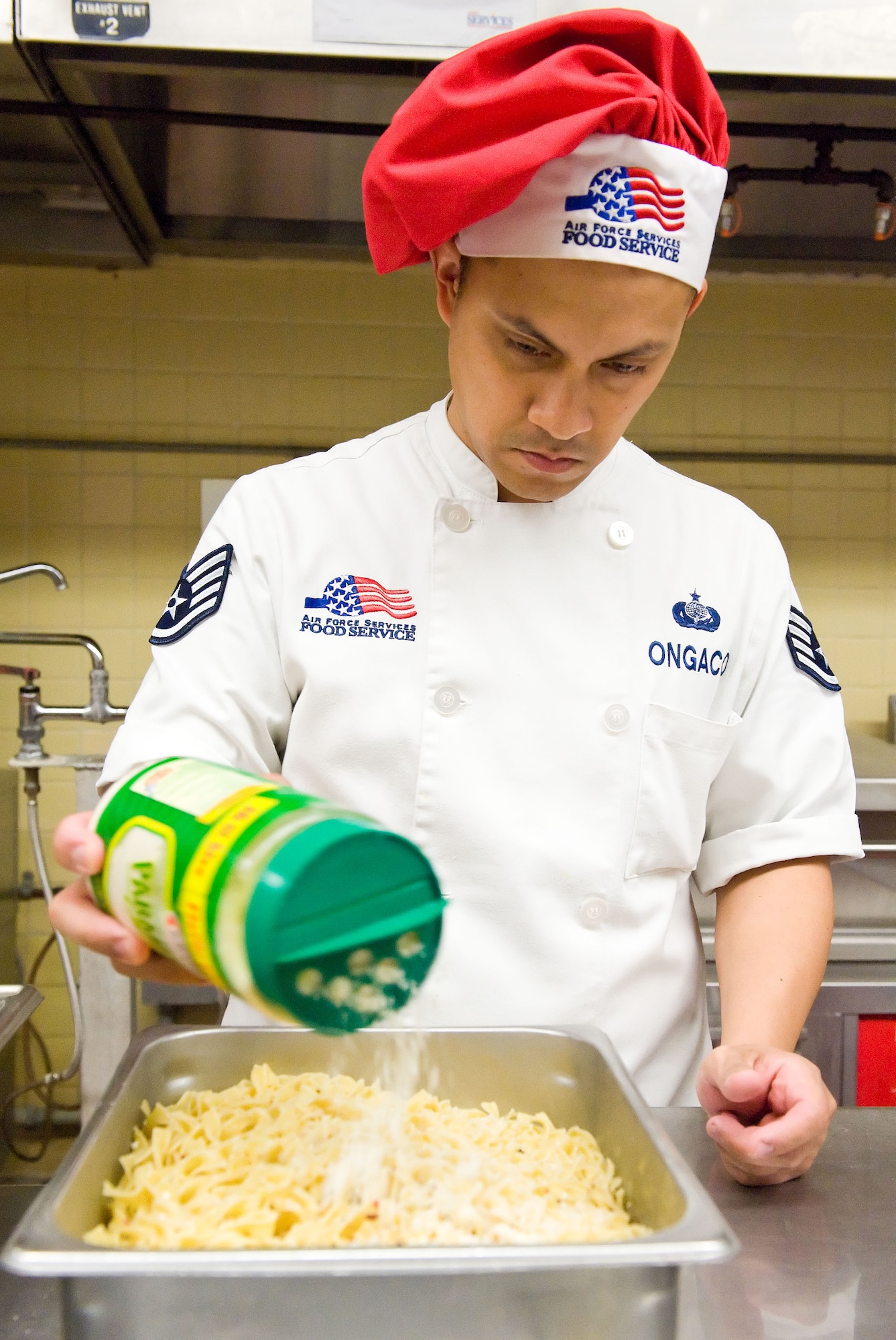 Staff Sgt. Rommel Ongaco, 436th Force Support Squadron food service supervisor, sprinkles Parmesan cheese over pasta March 28, 2014, at the Patterson Dining Facility on Dover Air Force Base, Del. Ongaco prepared the savory dish for the pasta bar. (U.S. Air Force photo/Roland Balik)