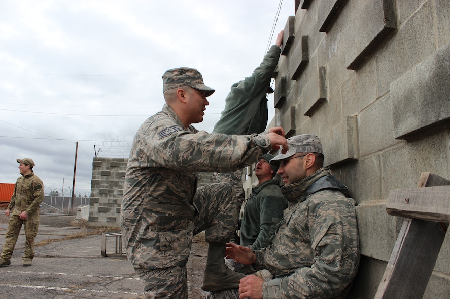 Staff Sgt. Joses Pineda, 368th Recruiting Squadron recruiter (left), prepares to climb a wall with the help of Tech. Sgt. Paul Willis, Military Entrance Processing Station liaison, during Survival, Evasion, Resistance and Escape training at Fairchild Air Force Base, Wash., March 5.  Members of the 368th RCS learned SERE techniques during squadron quarterly training in order to help them advise recruits who are interested in the SERE career field. (U.S. Air Force photo/Master Sgt. Mike Brown)
