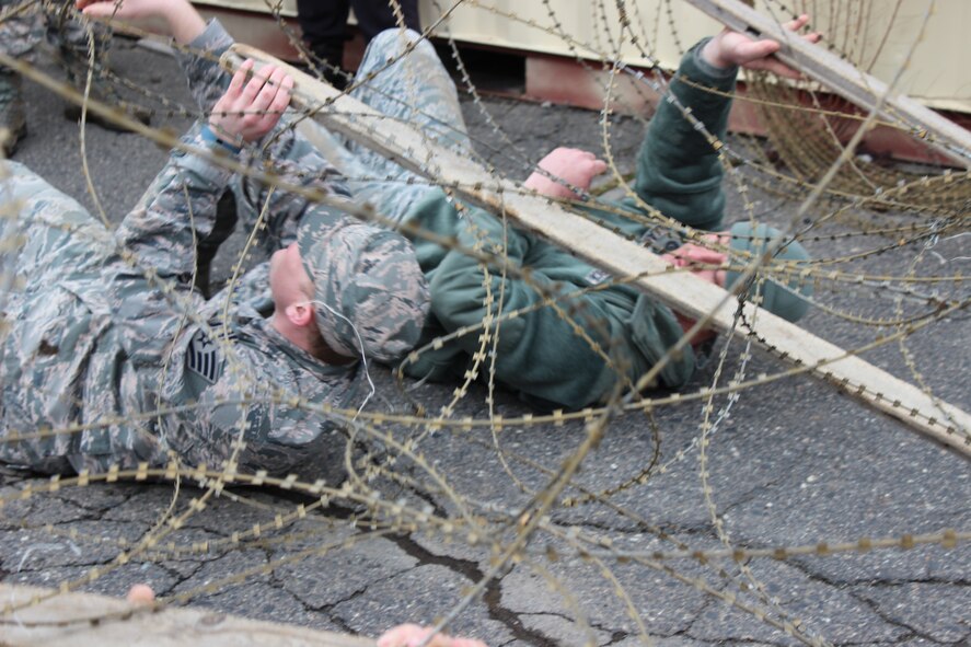 Staff Sgt. Christopher Ingram, 368th Recruiting Squadron recruiter (left), and Master Sgt. Richard Bullard, 368th RCS flight chief, crawl under razor wire during Survival, Evasion, Resistance and Escape training at Fairchild Air Force Base, Wash., March 5.  Members of the 368th RCS learned SERE techniques during squadron quarterly training in order to help them advise recruits who are interested in the SERE career field. (U.S. Air Force photo/Master Sgt. Mike Brown)
