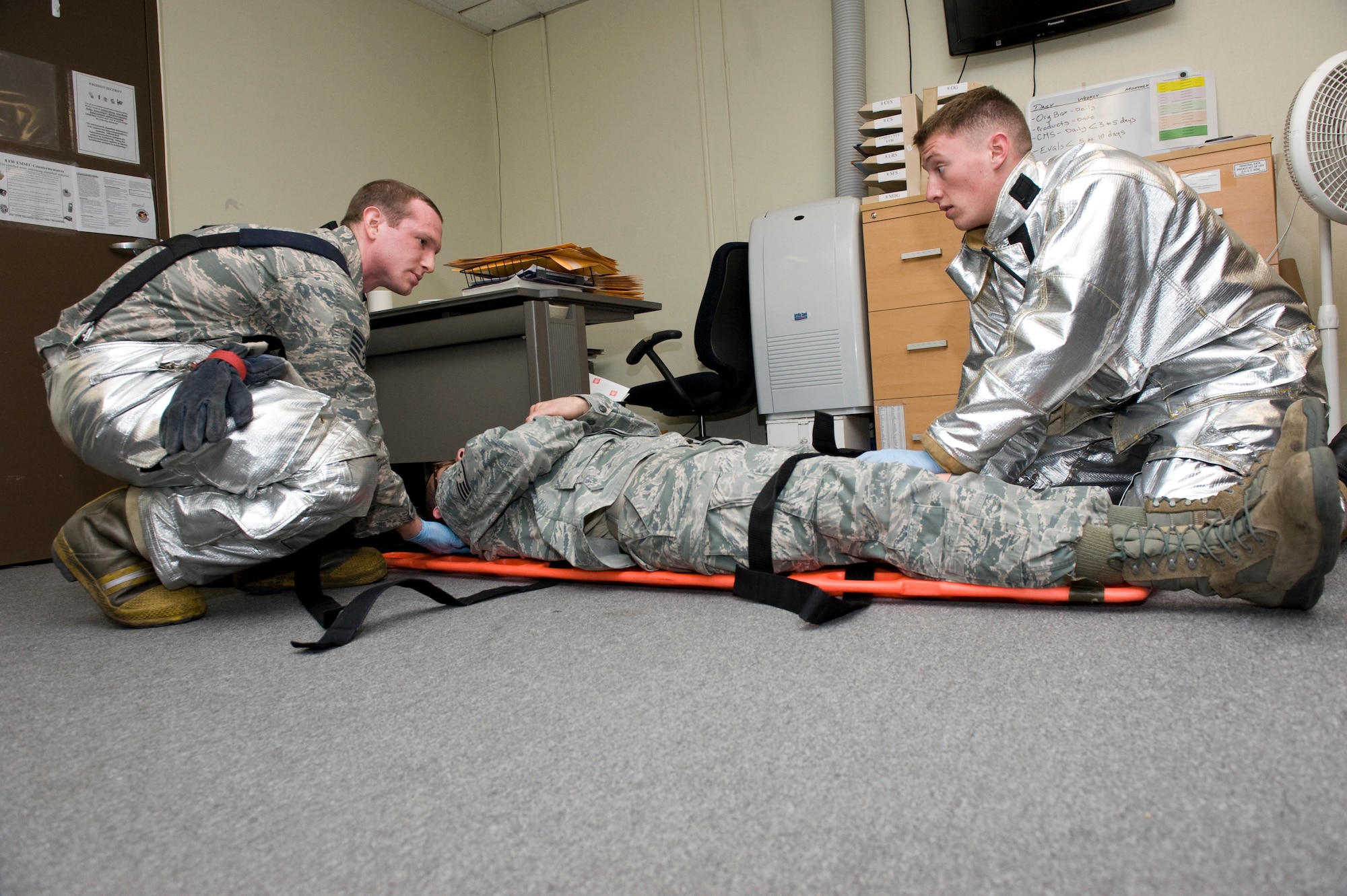 Eighth Civil Engineer Squadron firefighters Staff Sgt. Daniel Wool and Airman 1st Class Trevor McCleary provide care for injured role player Staff Sgt. Casey Sears, 8th Force Support Squadron force management journeyman, during the active shooter scenario at Kunsan Air Base, Republic of Korea, Apr. 8, 2014. The area was deemed safe and clear, allowing security forces members to begin aiding and moving the injured to safety. (U.S. Air Force photo by Staff Sgt. Jessica Haas/Released)