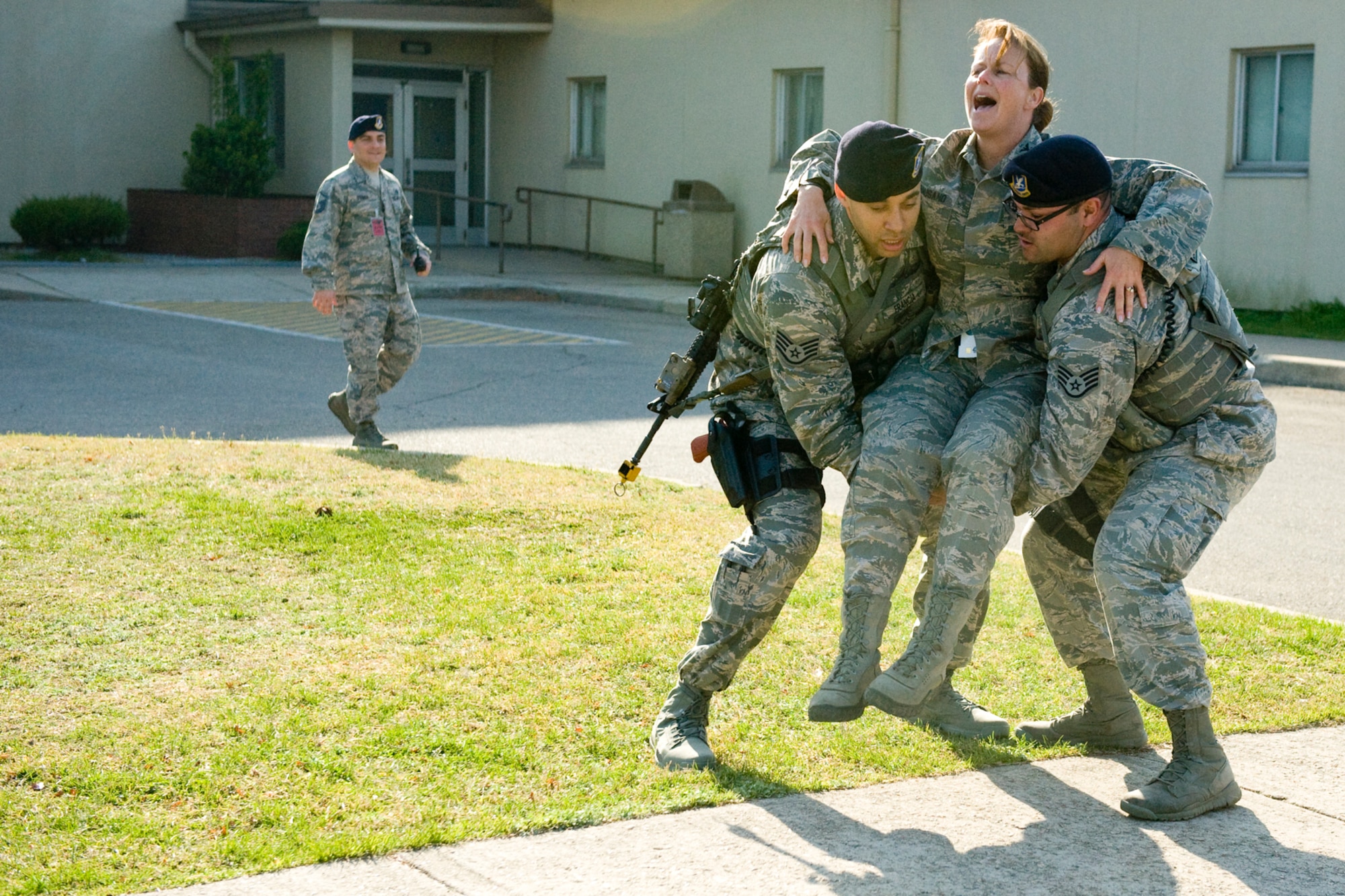 Col. Carrie J. Bausano, 8th Mission Support Group commander, acts injured as she is carried to safety by Staff Sgt. Jose Francia, 8th Security Forces Squadron military working dog handler, and Staff Sgt. Benjamin Rodriguez, 8th SFS MWD handler, during the active shooter scenario at Kunsan Air Base, Republic of Korea, Apr. 8, 2014. The area was deemed safe and clear, allowing security forces members to begin aiding and moving the injured to safety. (U.S. Air Force photo by Staff Sgt. Jessica Haas/Released)