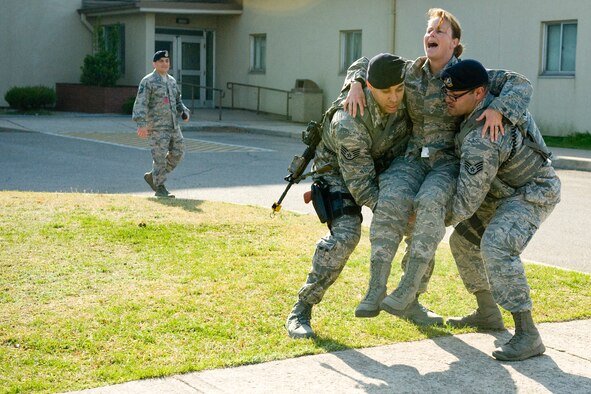 Col. Carrie J. Bausano, 8th Mission Support Group commander, acts injured as she is carried to safety by Staff Sgt. Jose Francia, 8th Security Forces Squadron military working dog handler, and Staff Sgt. Benjamin Rodriguez, 8th SFS MWD handler, during the active shooter scenario at Kunsan Air Base, Republic of Korea, Apr. 8, 2014. The area was deemed safe and clear, allowing security forces members to begin aiding and moving the injured to safety. (U.S. Air Force photo by Staff Sgt. Jessica Haas/Released)