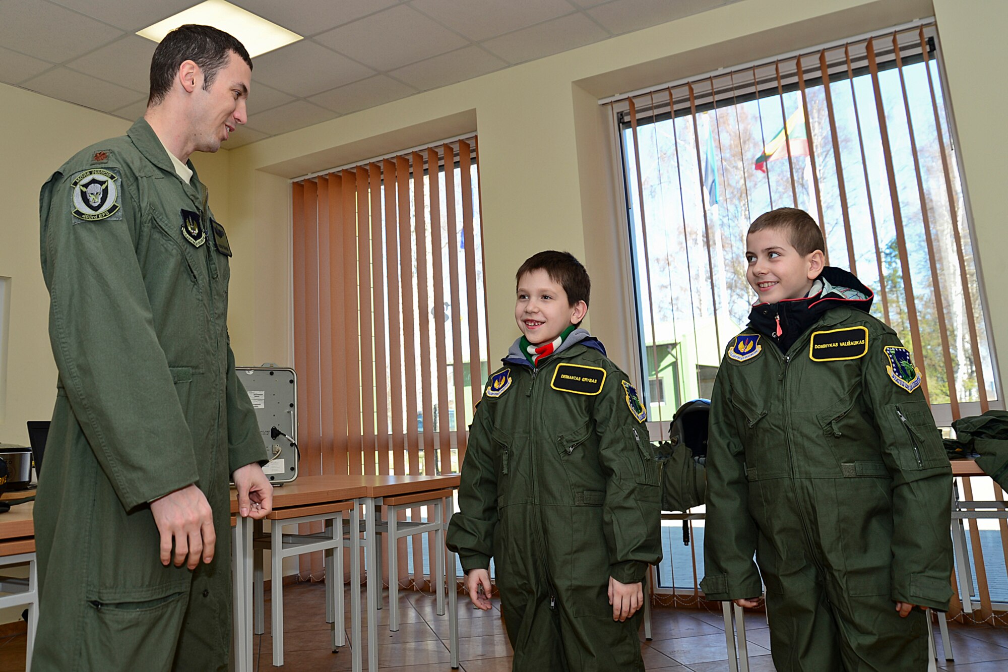 Major Jason Bianchi, 493rd Expeditionary Fighter Squadron pilot, ends the ‘Pilot for the Day’ event by giving Dominykas Vališaukas and Deimantas Grybas their honorary pilot wings at Šiauliai Air Base, Lithuania, April 4, 2014. ‘Pilot for a Day’ gives local children with serious illnesses and conditions a day away from routine hospital visits to see the U.S. Air Force mission up close. (U.S. Air Force photo by Airman 1st Class Dana J. Butler/Released)