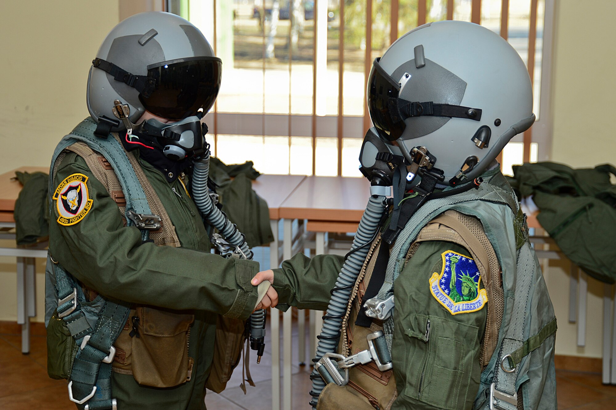 Dominykas Vališaukas and Deimantas Grybas shake hands after being suited up in aircrew flight equipment during the ‘Pilot for the Day’ event at Šiauliai Air Base, Lithuania, April 4, 2014. ‘Pilot for a Day’ gives local children with serious illnesses and conditions a day away from routine hospital visits to see the U.S. Air Force mission up close. (U.S. Air Force photo by Airman 1st Class Dana J. Butler/Released)