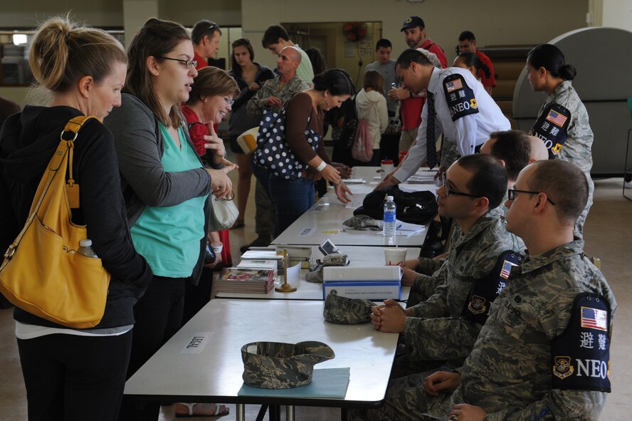 Volunteers from different organizations on base set up tables to answer questions that the Non-combatant Evacuation Operation volunteers may have during a NEO exercise on Kadena Air Base, Japan, April 4, 2014. These organizations included the legal office, the chaplain office, a medical team, and a TRICARE representative. This NEO exercise was set up by the Airman and Family Readiness Center to help dependents and other non-combatants understand the evacuation process in the event of an emergency that would make it unsafe for them to remain on island. (U.S. Air Force photo by Airman 1st Class Zackary A. Henry)
