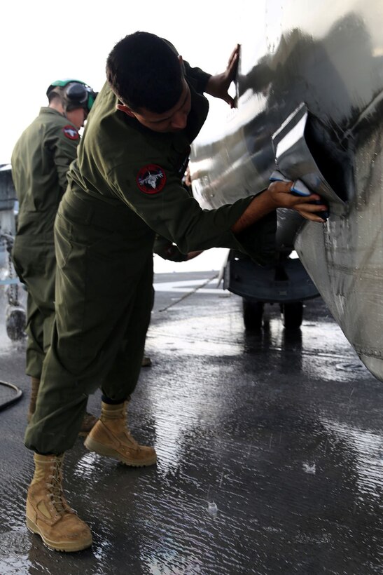 A Marine with Marine Medium Tiltrotor Squadron 163 (Reinforced), 11th Marine Expeditionary Unit, cleans the side of an AV-8B Harrier aboard the USS Makin Island during Amphibious Squadron Marine Expeditionary Unit Integration Training (PMINT) off the coast of San Diego, Calif., April 8, 2014.  PMINT is a two-week predeployment training event focused on the combined capabilities of the MEU and Amphibious Ready Group (ARG), conducting amphibious operations, crisis response and limited contingency operations.  (U.S. Marine Corps photo by Lance Cpl. Laura Y. Raga/Released)