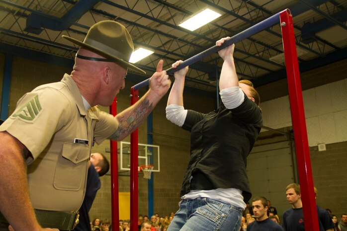 Staff Sgt. Nicholas A. Carrel, a Drill Instructor from Marine Corps Recruit Depot San Diego, motivates a poolee during a partial Initial Strength Test at Recruiting Substation Green Bay’s Family Nights pool function, Apr. 3.  Family Nights give poolees their first glimpse into Marine Corps recruit training and allow family members to voice any questions or concerns they may have about recruit training.