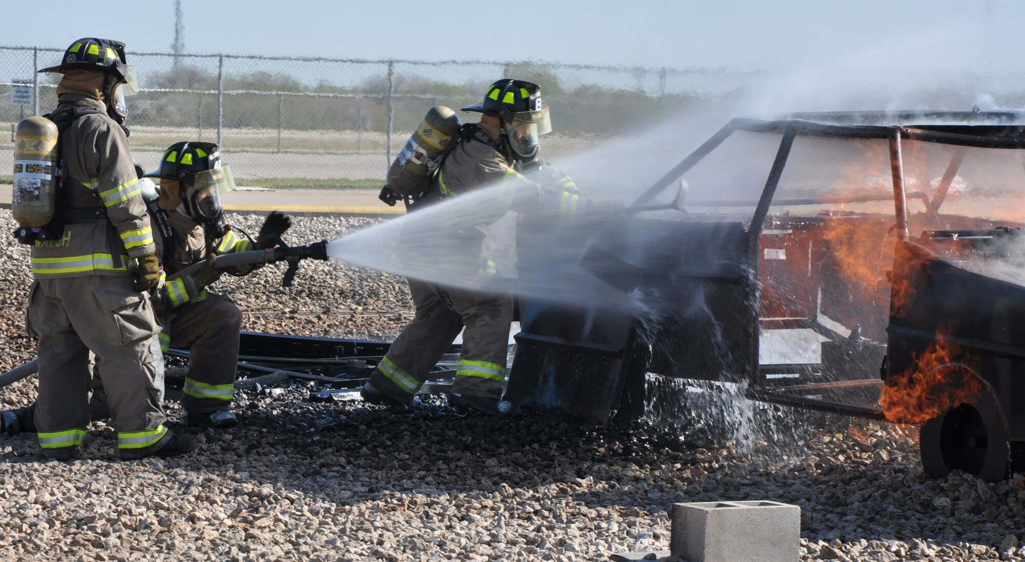 GOODFELLOW AIR FORCE BASE, Texas – Bryce W. Bell, San Angelo Fire Department recruit, sprays a car fire at the Louis F. Garland Department of Defense Fire Academy here April 9. During the firefight, Kellen R. Geirke, SAFD recruit, used a forcible entry tool to simulate breaking the car windows and to prop open the hood. (U.S. Air Force photo/ Senior Airman Joshua Edwards)