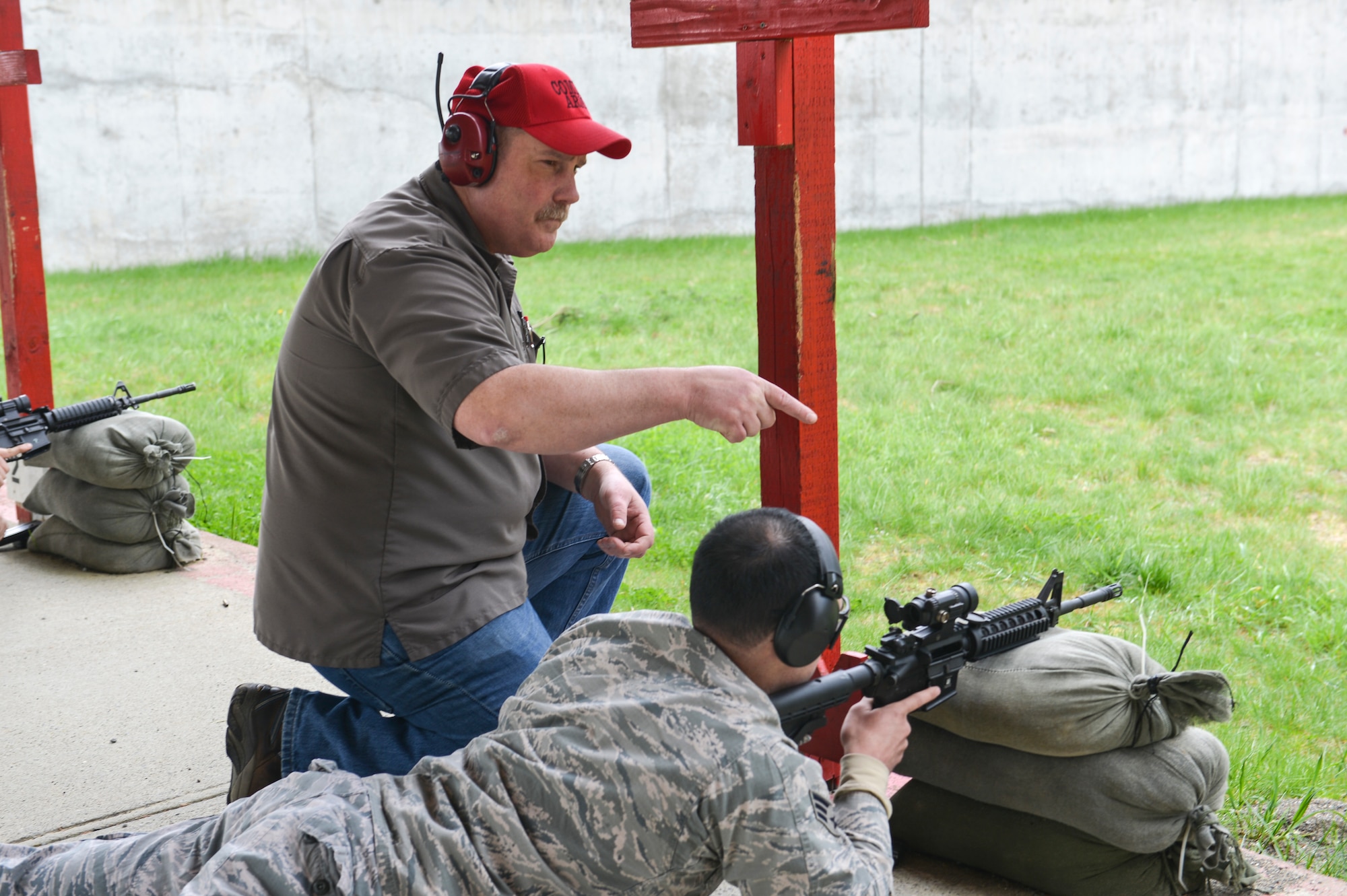 Richard Jette, 627th Security Forces Squadron combat arms instructor, adjusts the shooting position of Senior Airman Kevin Alfonso, 627 Civil Engineer Squadron firefighter, at Range 108 next to North Fort Lewis, April 9, 2014 at Joint Base Lewis-McChord, Wash. Civilians must complete the Combat Arms Apprentice Course at Joint Base San Antonio, Texas to become combat arms instructors for the Air Force. (U.S. Air Force photo/Staff Sgt. Russ Jackson)