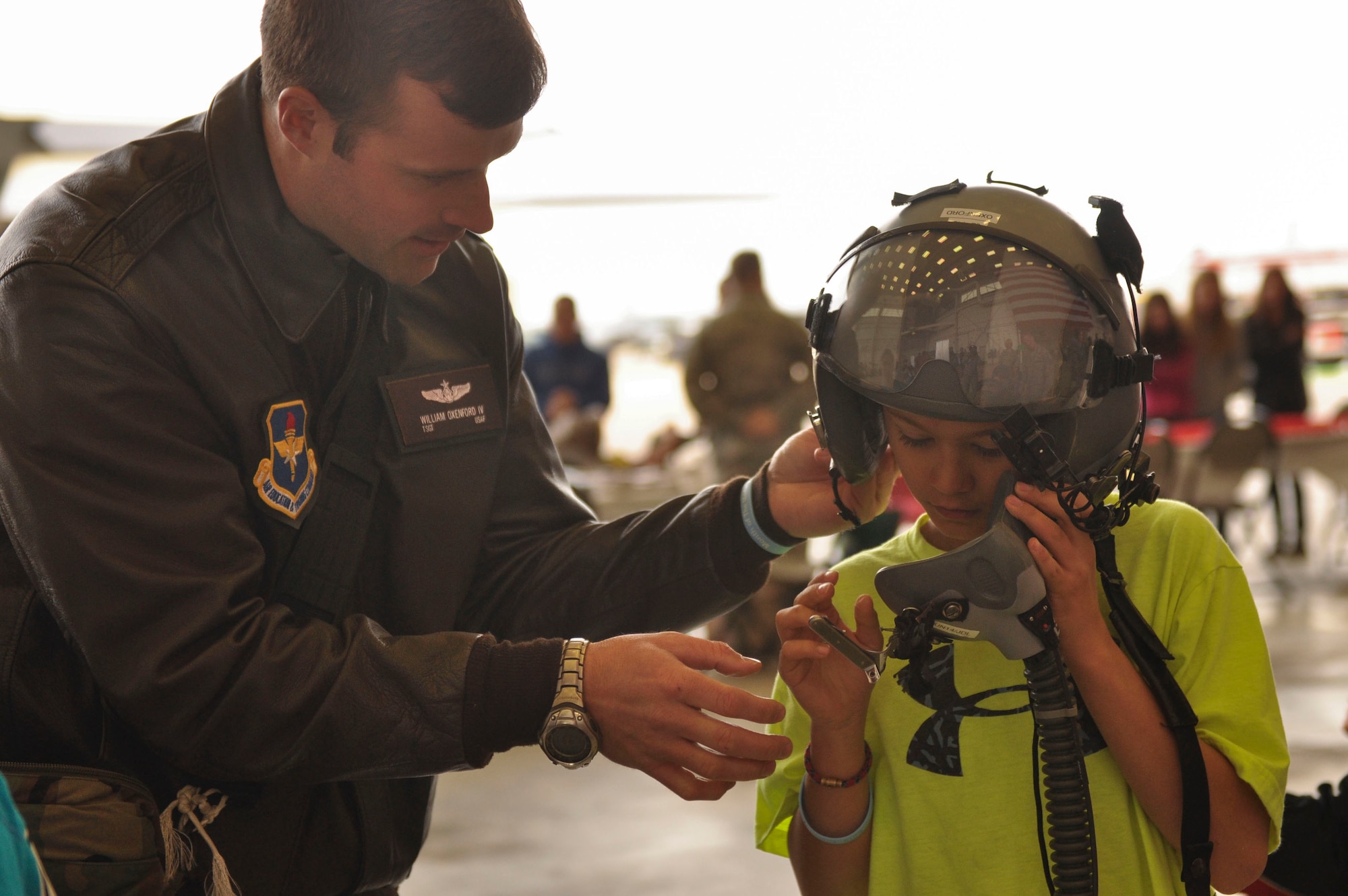 Tech. Sgt. William Oxenford IV, a 62nd Airlift Squadron formal training unit instructor loadmaster, assists a child with properly configuring an aviation helmet and mask for flight operations April 5 during the Kids Understanding Deployment Operations at Little Rock Air Force Base, Ark. This five-hour event was coordinated by the Airmen and Family and Readiness Center. (U.S. Air Force photo by Senior Airman Regina Agoha)