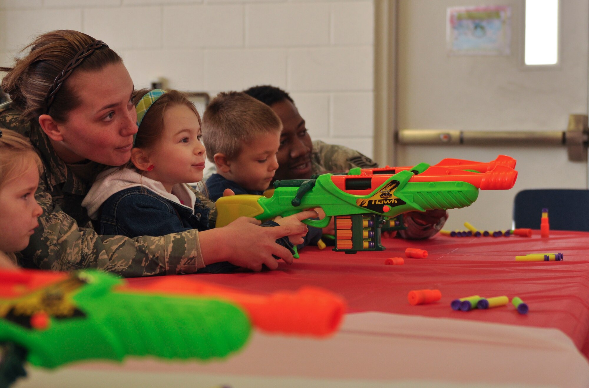 Airmen from the 19th Security Forces Squadron help children shoot at the nerf gun firing range section during the Kids Understanding Deployment Operations April 5 at Little Rock Air Force Base, Ark. McGruff the crime dog was also at the event. (U.S. Air Force photo by Senior Airman Regina Agoha)