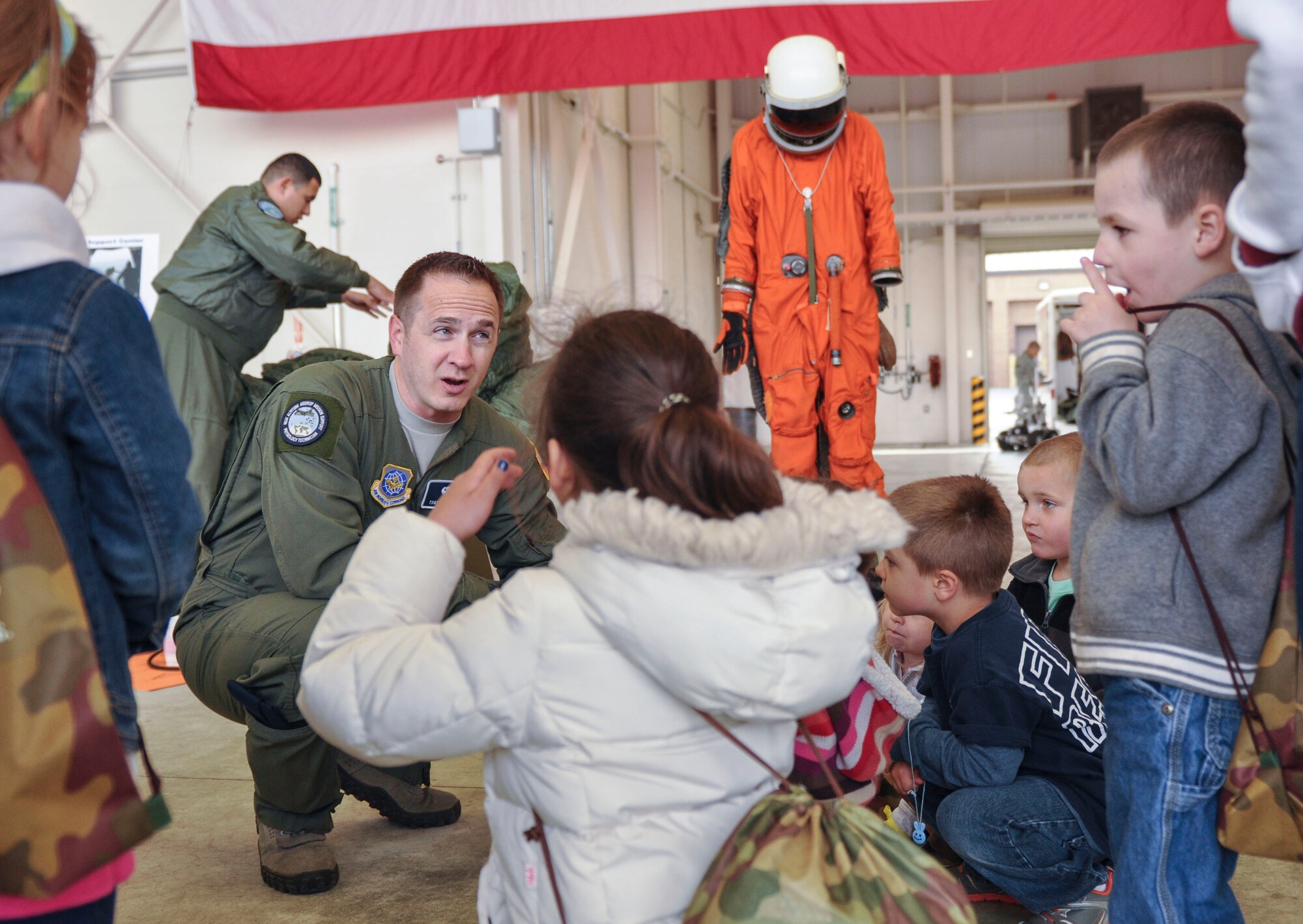 Tech. Sgt. Daniel Zerbe, 19th Medical Group noncommissioned officer in charge of aerospace and operational physiology, explains the high altitude airdrop mission to a group of children April 5 during the Kids Understanding Deployment Operations event at Little Rock Air Force Base, Ark. More than 750 Team Little Rock members participated in the event. (U.S. Air Force photo by Senior Airman Regina Agoha)