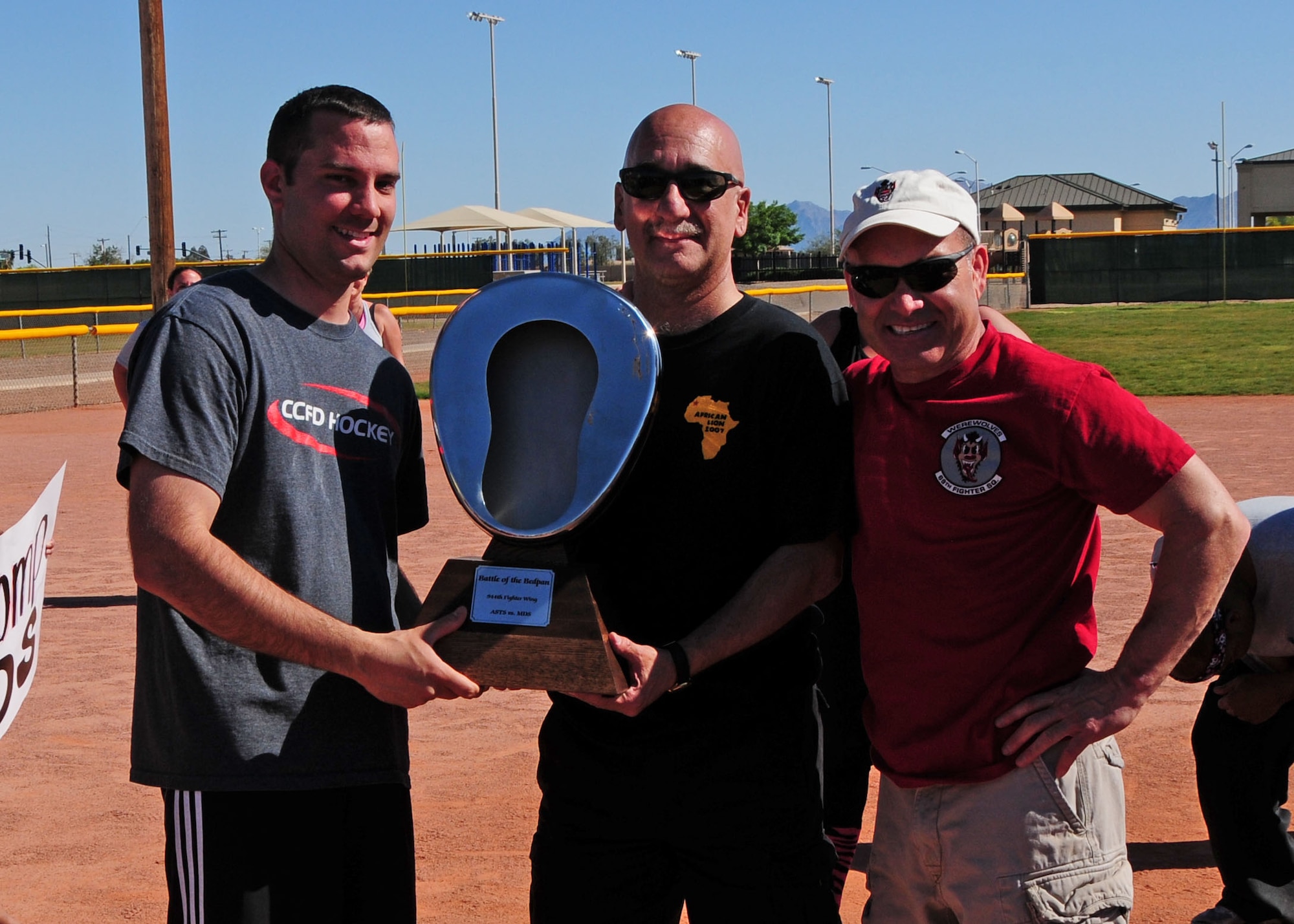 Col. Kurt Gallegos, 944th Fighter Wing commander, presents the “bed pan” trophy to Col. Curtiss Cook, 944th Aeromedical Staging Squadron commander and Staff. Sgt. Kevin Maiorano, 944th Aeromedical Staging Squadron medical technician, April 6 after winning a friendly softball game against the 944th Medical Squadron at Luke Air Force Base, Ariz. Maiorano and Master Sgt. Henry Ruiz, 944th Medical Squadron diet therapy technician, were the squadron representatives in charge of organizing the event. (U.S. Air Force photo taken by Tech. Sgt. Louis Vega Jr.)