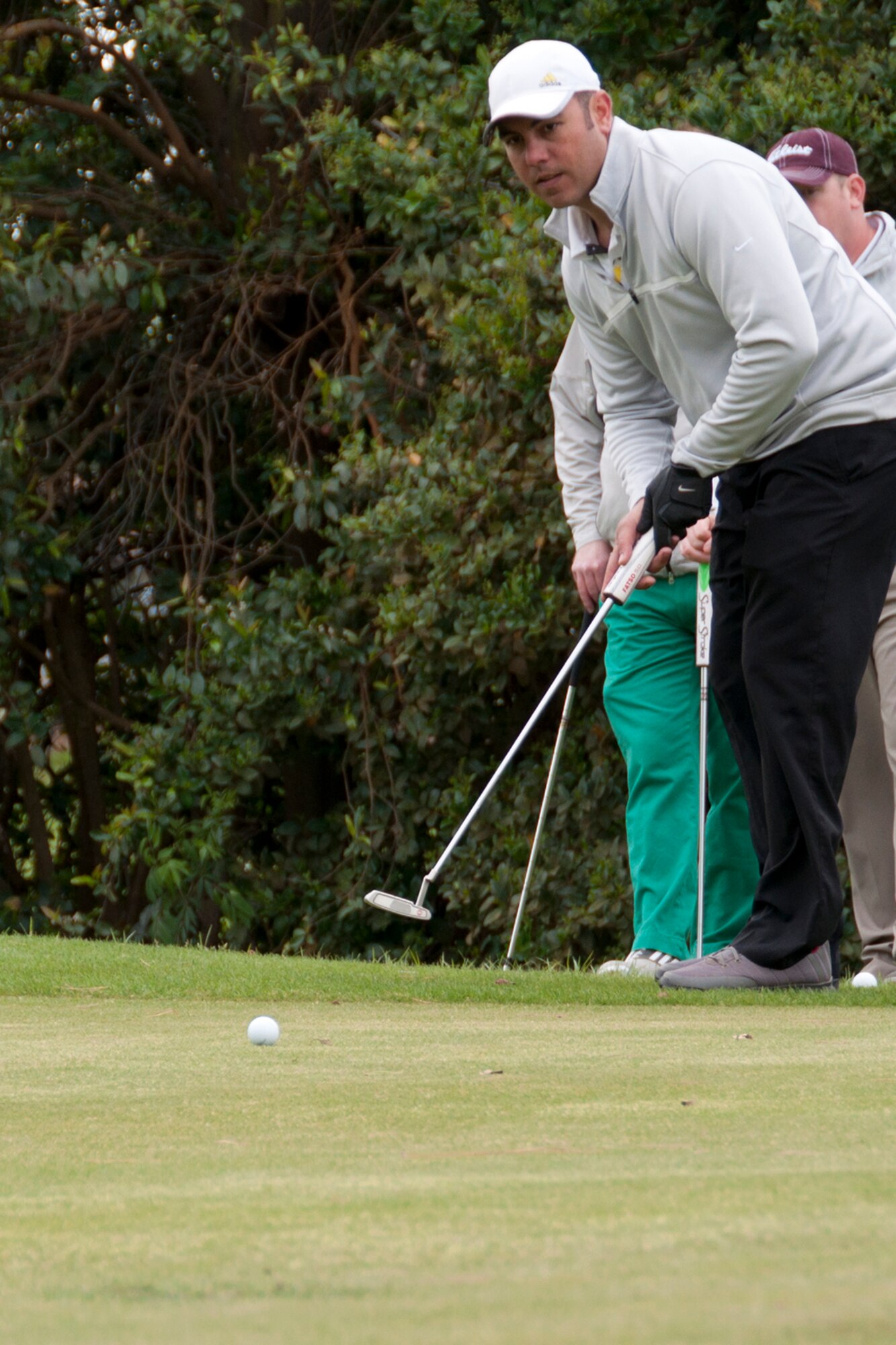 Jonathon Wilson looks on intently as his putt roles to the cup during the 307th Bomb Wing Commander's Cup at Barksdale Air Force Base, La., April 05, 2014.  Despite damp turf and cool, windy conditions, a majority of the teams in the event finished under par for the day. (U.S. Air Force photo by Tech. Sgt. Ted Daigle/Released)