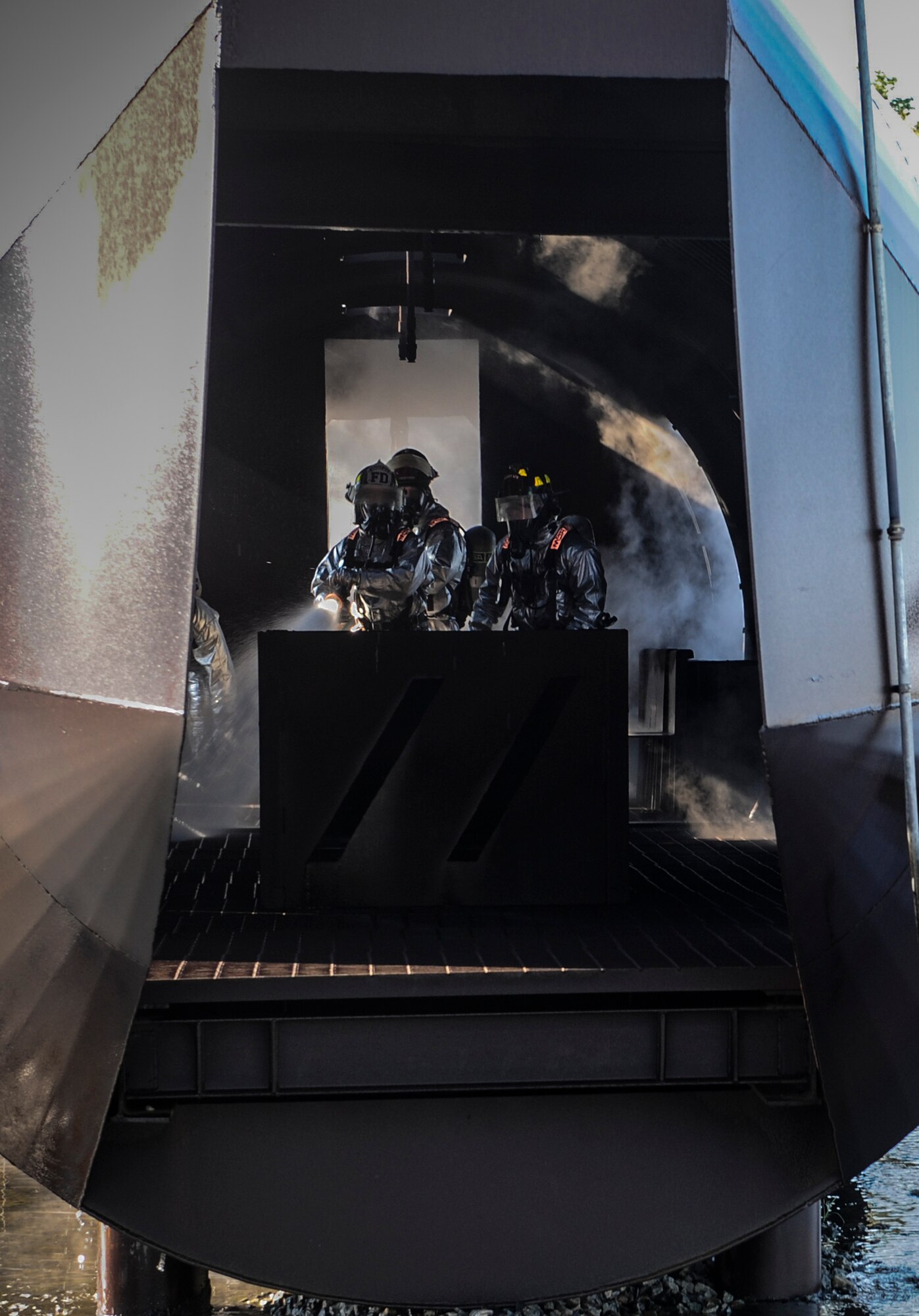 Fire emergency services Airmen from the 23d Civil Engineer Squadron hose down the inside of a mock C-130 aircraft at the fire department training pit on Moody Air Force Base, Ga., April 9, 2014. The training is completed quarterly to ensure Airmen remain proficient on their job duties. (U.S. Air Force photo by Airman 1st Class Alexis Millican/Released)