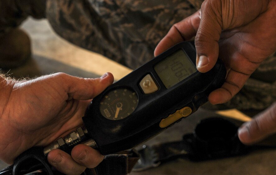Airmen check the air level in an oxygen tank using a pass device at Moody Air Force Base, Ga., April 9, 2014. Firefighters use the oxygen tanks to help them breath while searching through burning buildings. (U.S. Air Force photo by Airman 1st Class Alexis Millican/Released)