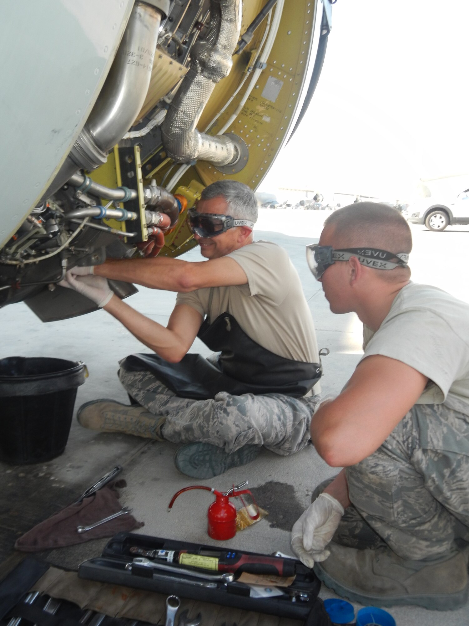 Brig. Gen. Roger Watkins, 379th Air Expeditionary Wing commander, assists Senior Airman Brandon Mayer, a 379th Expeditionary Aircraft Maintenance Squadron aerospace propulsion technician, with routine oil servicing of a jet fuel starter on a RC-135V/W Rivet Joint reconnaissance aircraft at Al Udeid Air Base, Qatar, April 8, 2014.  Scheduled inspections afford maintainers the opportunity to accomplish preventative actions and posture the aircraft to perform at its maximum potential, providing near real time on-scene intelligence collection, analysis and dissemination capabilities.  Watkins periodically engages with maintenance Airmen to learn about the issues they encounter while generating combat aircraft in support of Operation Enduring Freedom.  Mayer is deployed from Offutt Air Force Base and a native of Naples, N.Y.  Watkins is stationed at AUAB and hails from Fort Worth, TX. (U.S. Air Force photo by Staff Sgt. Miguel Marrera) 