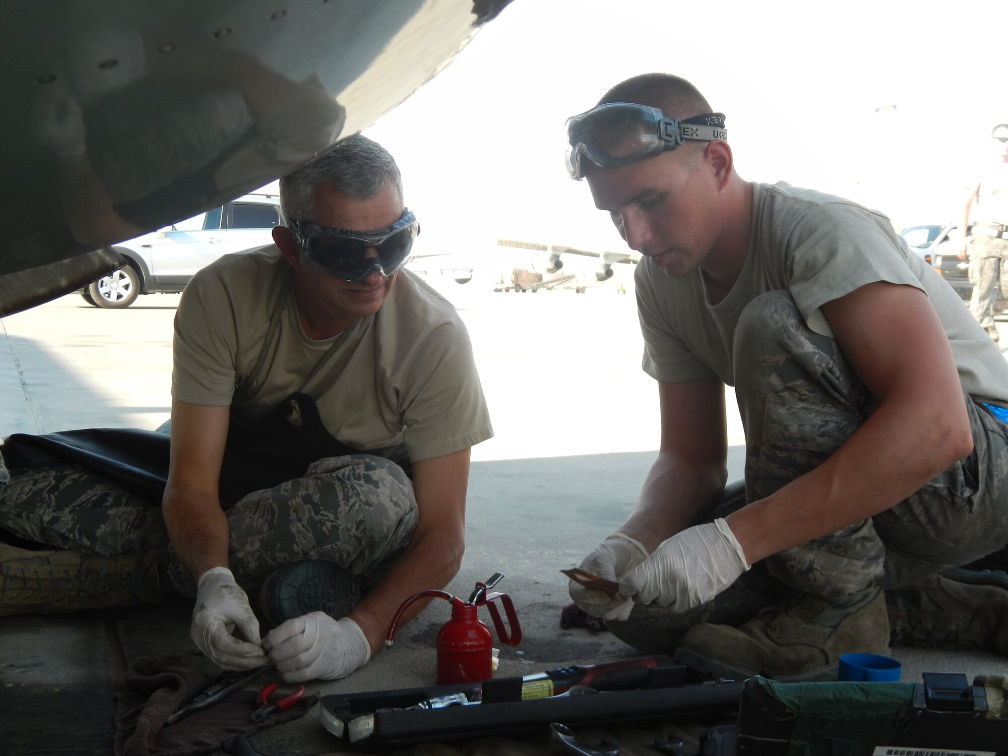 Brig. Gen. Roger Watkins, 379th Air Expeditionary Wing commander, assists Senior Airman Brandon Mayer, a 379th Expeditionary Aircraft Maintenance Squadron aerospace propulsion technician, with routine oil servicing of a jet fuel starter on a RC-135V/W Rivet Joint reconnaissance aircraft at Al Udeid Air Base, Qatar, April 8, 2014.  Scheduled inspections afford maintainers the opportunity to accomplish preventative actions and posture the aircraft to perform at its maximum potential, providing near real time on-scene intelligence collection, analysis and dissemination capabilities.  Watkins periodically engages with maintenance Airmen to learn about the issues they encounter while generating combat aircraft in support of Operation Enduring Freedom.  Mayer is deployed from Offutt Air Force Base and a native of Naples, N.Y.  Watkins is stationed at AUAB and hails from Fort Worth, TX. (U.S. Air Force photo by Staff Sgt. Miguel Marrera) 
