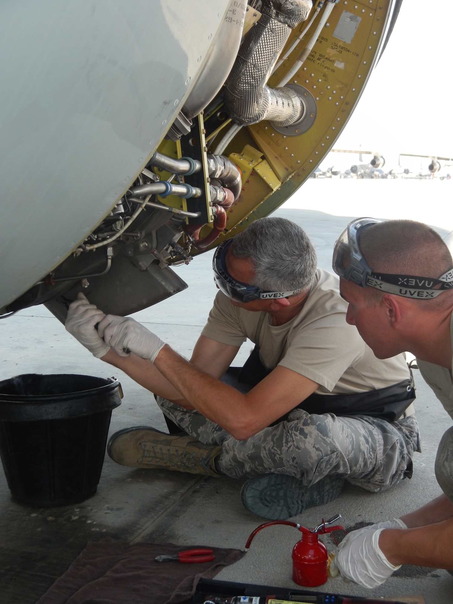 Brig. Gen. Roger Watkins, 379th Air Expeditionary Wing commander, assists Senior Airman Brandon Mayer, a 379th Expeditionary Aircraft Maintenance Squadron aerospace propulsion technician, with routine oil servicing of a jet fuel starter on a RC-135V/W Rivet Joint reconnaissance aircraft at Al Udeid Air Base, Qatar, April 8, 2014.  Scheduled inspections afford maintainers the opportunity to accomplish preventative actions and posture the aircraft to perform at its maximum potential, providing near real time on-scene intelligence collection, analysis and dissemination capabilities.  Watkins periodically engages with maintenance Airmen to learn about the issues they encounter while generating combat aircraft in support of Operation Enduring Freedom.  Mayer is deployed from Offutt Air Force Base and a native of Naples, N.Y.  Watkins is stationed at AUAB and hails from Fort Worth, TX. (U.S. Air Force photo by Staff Sgt. Miguel Marrera) 